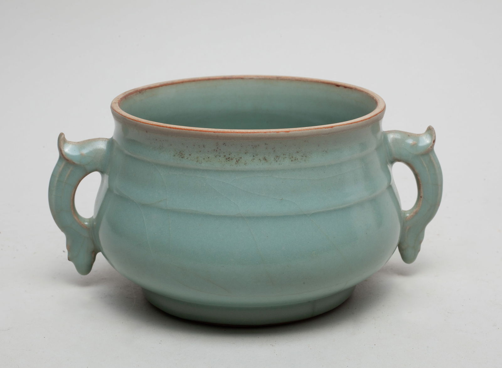 Chinese Longquan Porcelain Censer: Of compressed globular form with a broad mouth, set with two handles, covered overall in celadon glaze with natural crackles. Approx. 8*6.2*4 inch.