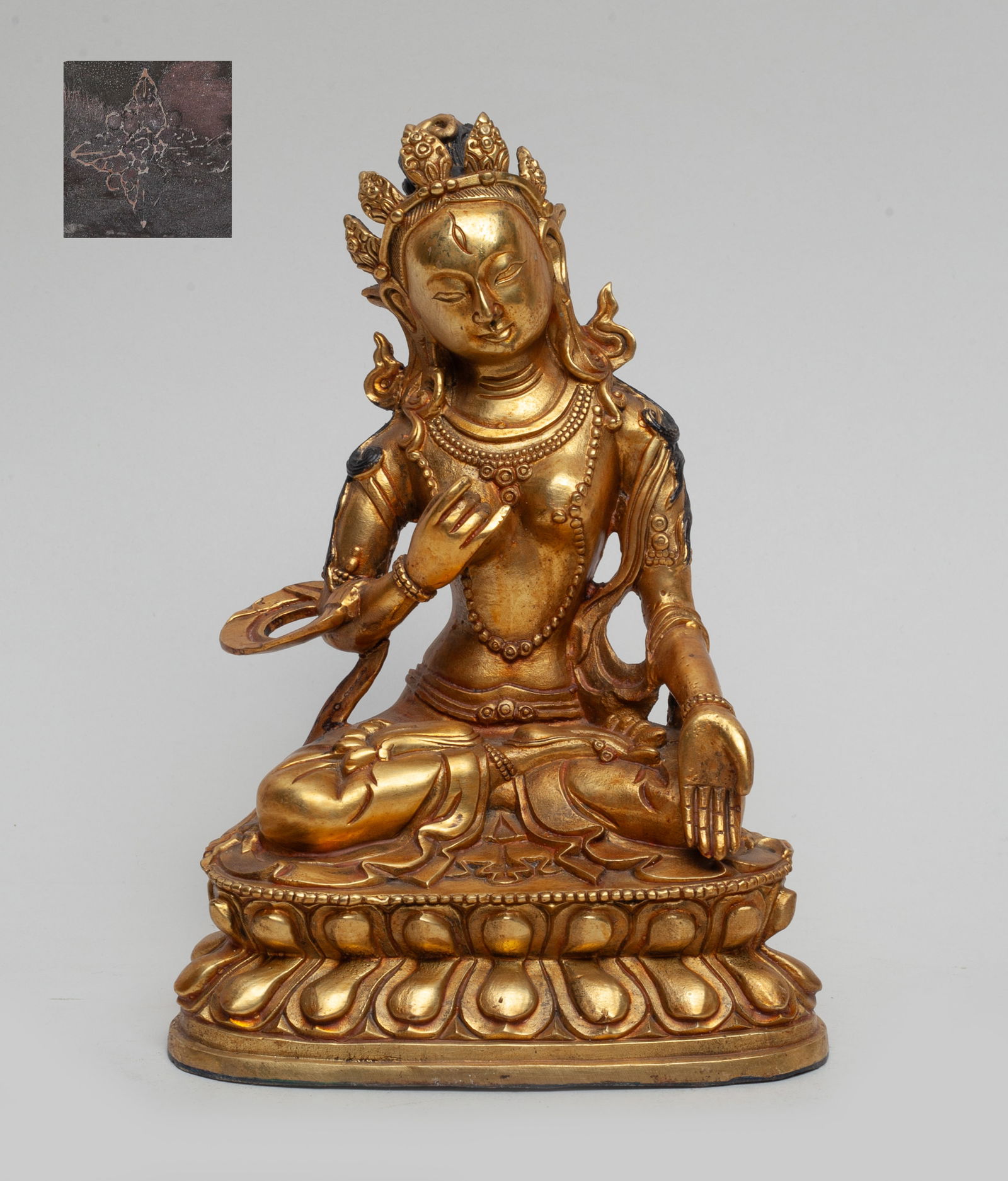 Chinese Gilt Bronze Buddha: The Buddha seated cross legged on a double lotus throne, the left hand in varadamudra and the right hand in karanamudra, adorned with a tall diadem and beaded jewelry, the underside incised with a Bud