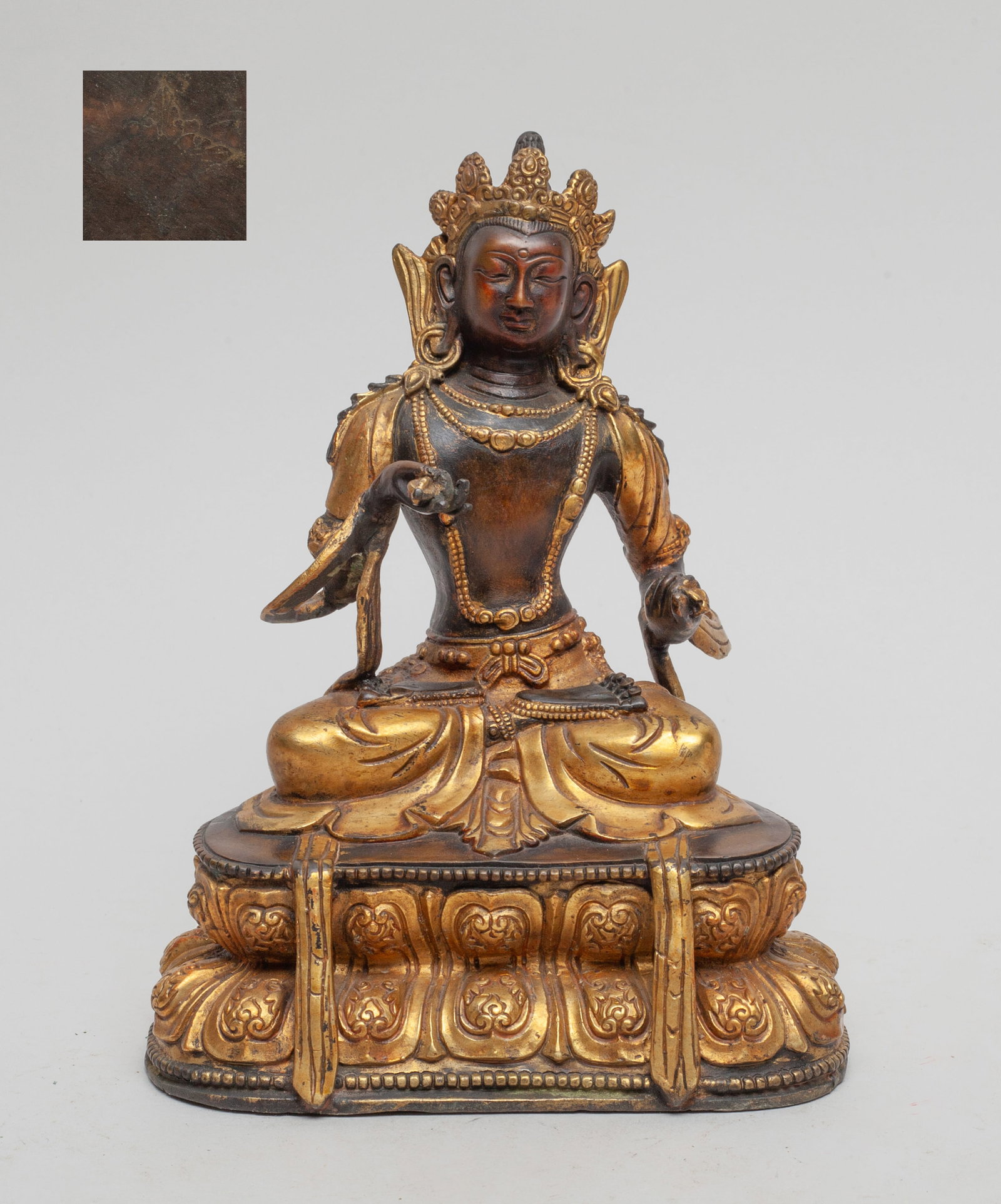 Chinese Sino-Tibetan Gilt Bronze Buddha: The Buddha seated cross legged on a double lotus throne, the hands holding vajra, wearing a long scarf and a dhoti decorated with bead jewelry, the underside incised with a Buddhist symbol. Approx. 7*