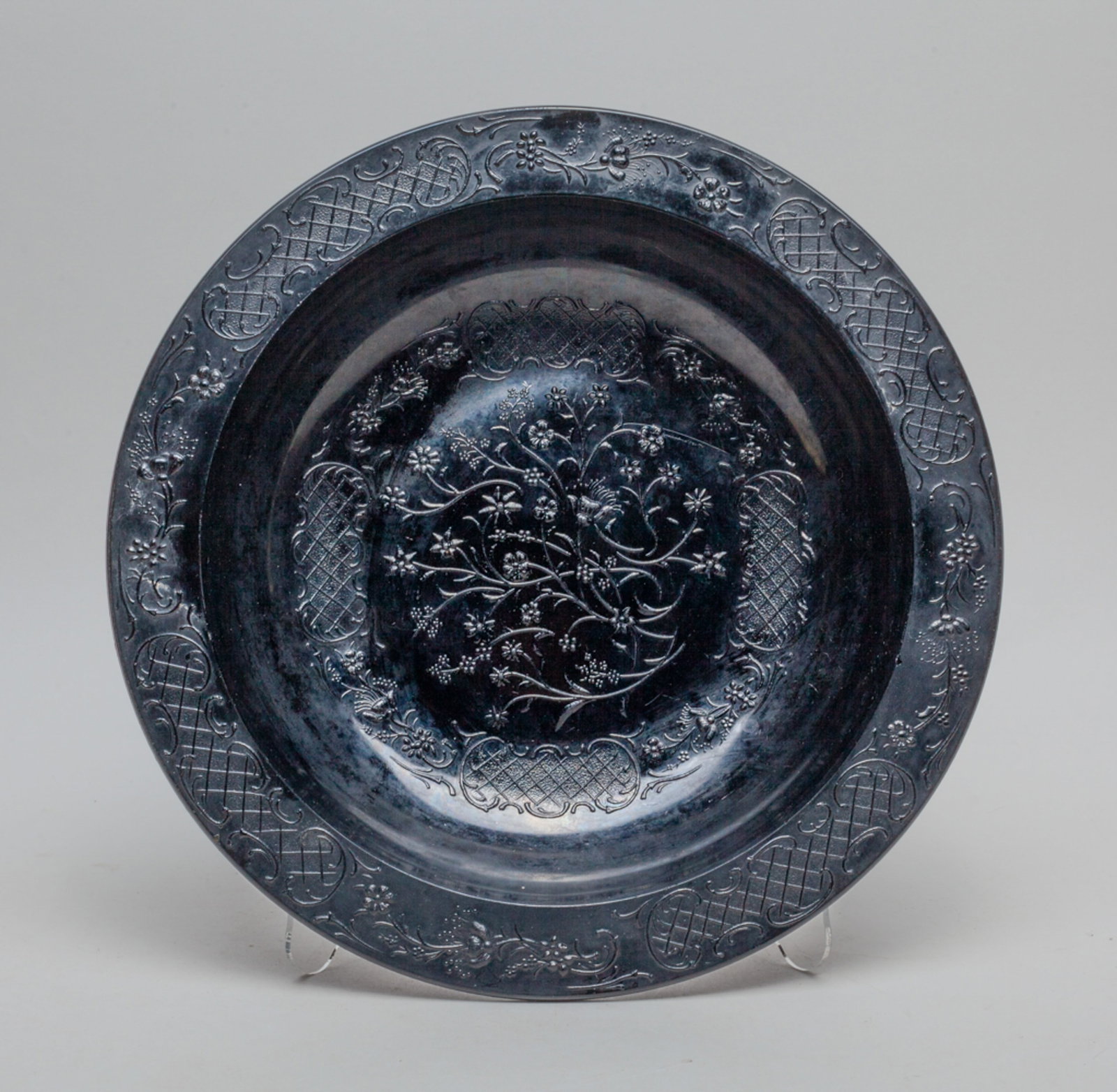 Victorian Glass Large Bowl: The large glass bowl in black tone, with a wider flat rim and three short knob at the bottom as legs, interior overall molded with intricate slender flower motif in the center surrounded by a band of 
