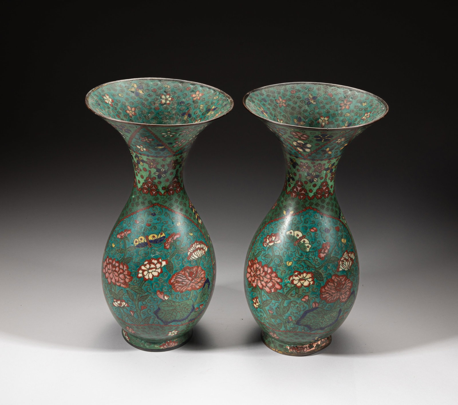 Pair Japanese Edo Cloisonne Vases: A pair of Japanese cloisonne vases of ovoid form rising from a short foot to a waisted neck with flared mouth, enameled with butterflies and various flowers on dark green ground. Approx. 12*6.4 inch (
