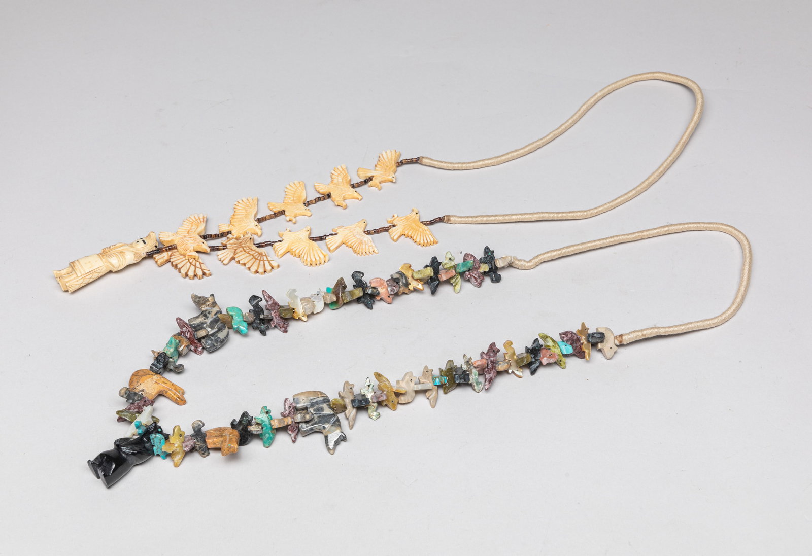 Zuni Fetish Necklaces: Two Zuni fetish necklaces, one with multi-gemstone pendants carved in various animal form, the other with bone pendants carved in eagle and figure form. Approx. 33inch L (larger).