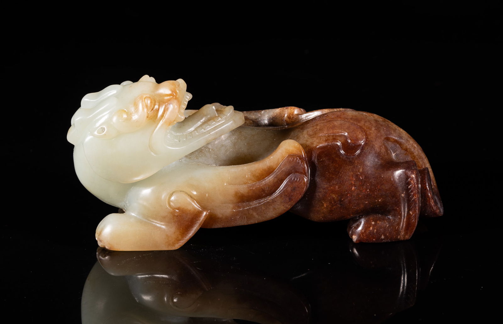 Large Chinese Jade Sculpture of Beast: Chinese pale celadon and russet jade beast, finely modelled recumbent and resting on its haunches with paws, its head turned sharply over the shoulder, the facial features well defined with bulging ey