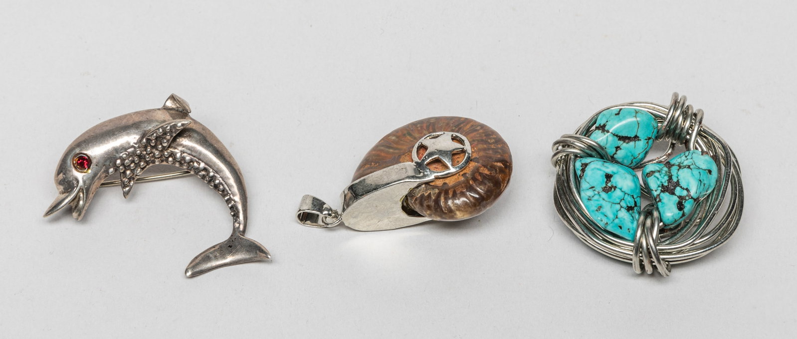 Fossilized Stone, Turquoise Sterling Jewelry: Including a sterling and turquoise-like stone pendant, a fossilized stone pendant, and a dolphin form brooch. Size varies.