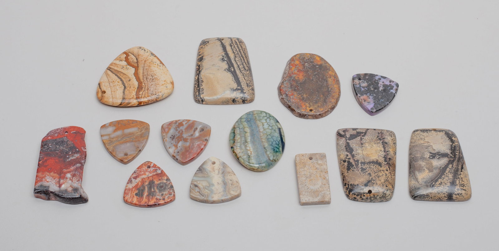 Fossilized Stone & Jasper Plaque Pendants: Group of 13 fossilized stone and jasper carved plaques and pendants. Size varies.