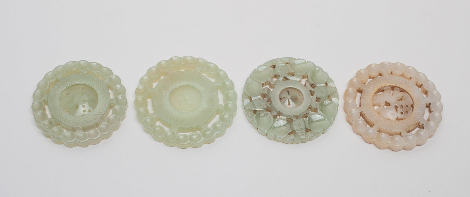 Set Chinese Jade Pendants: Set of four jade pendants with rotating centers, wherein two carved with a central Fu character, one carved with a central swastika symbol, and the other one carved with four bats. Approx. 2.2inch W (