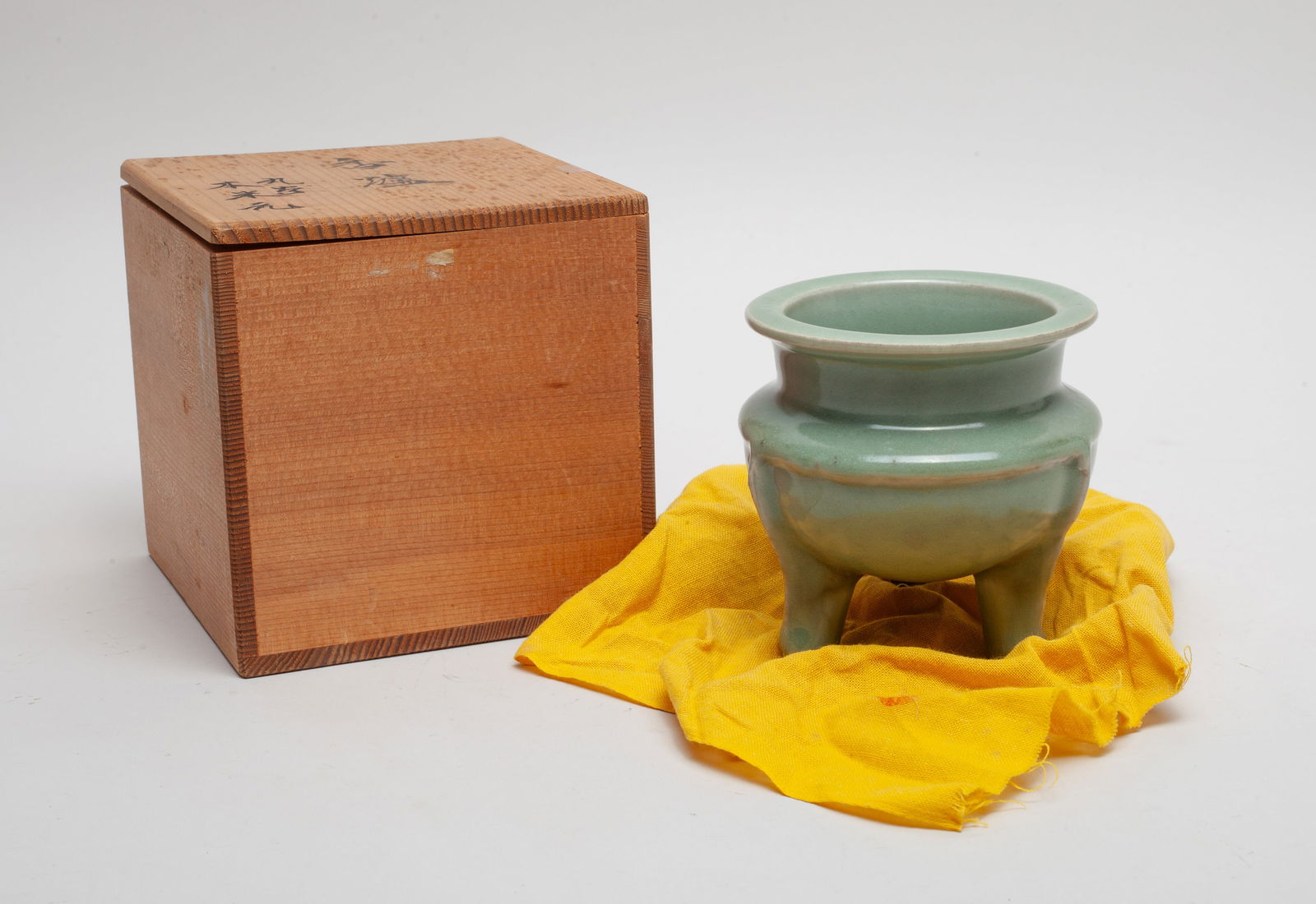 Chinese Longquan Ware Porcelain Censer: The compressed ovoid body rising to a short neck and everted rim, supported on three cylindrical legs, overall covered in celadon glaze, with a covered box. Approx. 4.2*4.1 inch (w/o box).