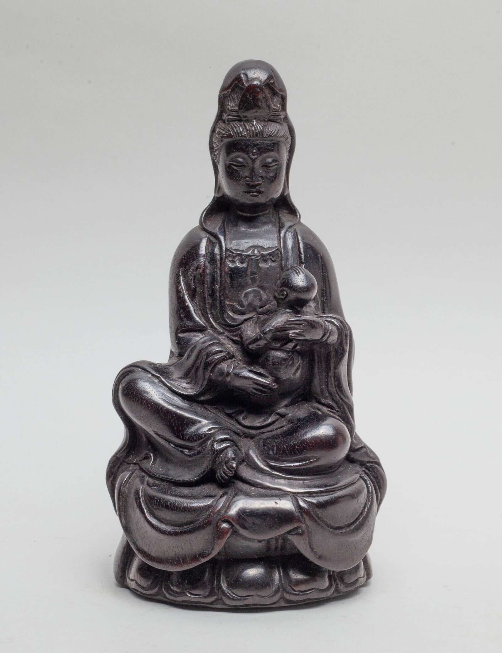 Chinese Zitan Like Wood Sculpture of Buddha: Well-carved kuanyin with serene expression, seated with her knees and carried a boy, crossed wearing long robes draping from the shoulders before elegantly falling into neat voluminous folds over the 