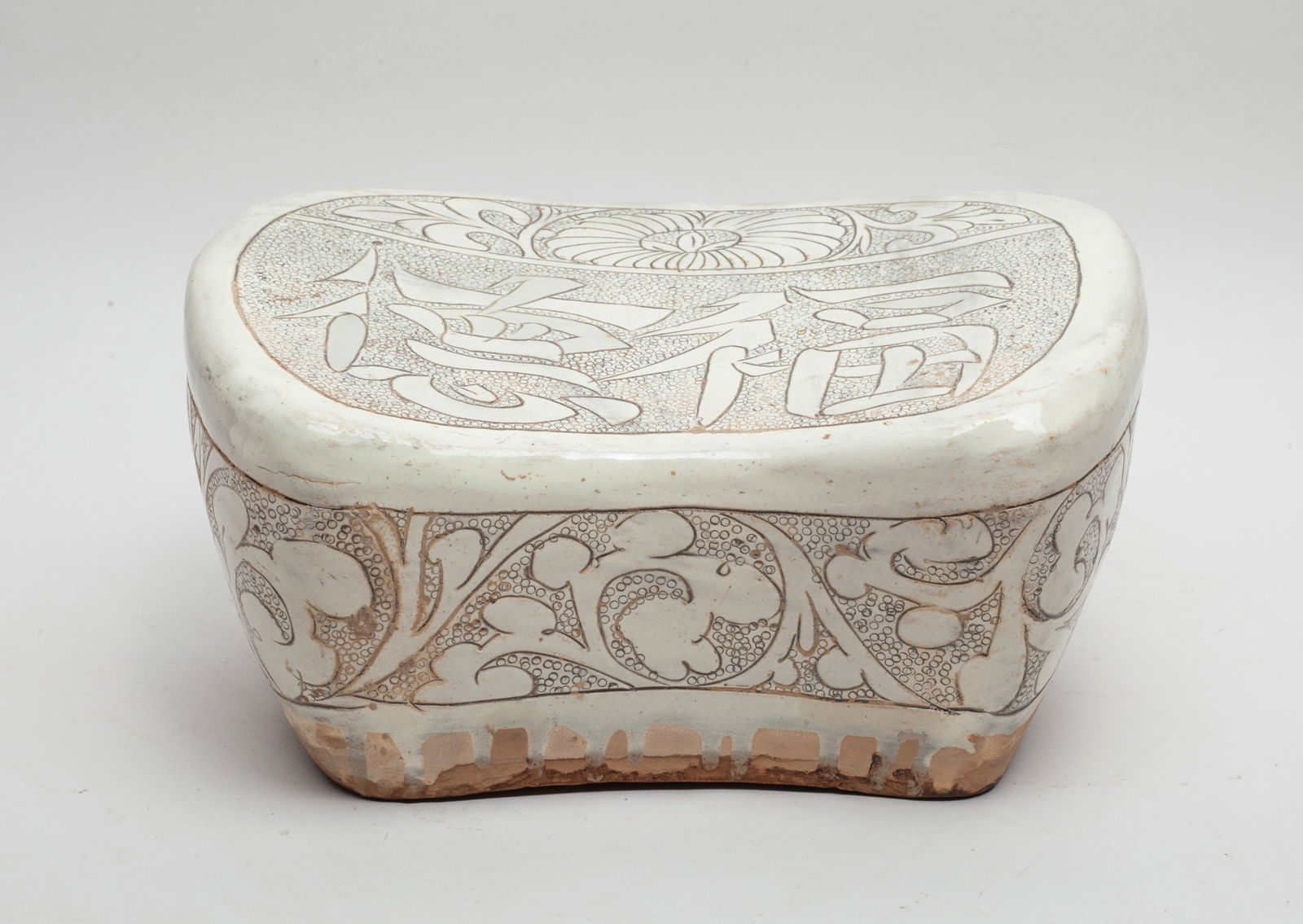 Large Chinese Porcelain Pillow: The pillow top side carved with two large characters and a flower, the sides with undulating foliage sprays, the ground suffused with small circles. Approx. 10*6.5*5.1 inch.