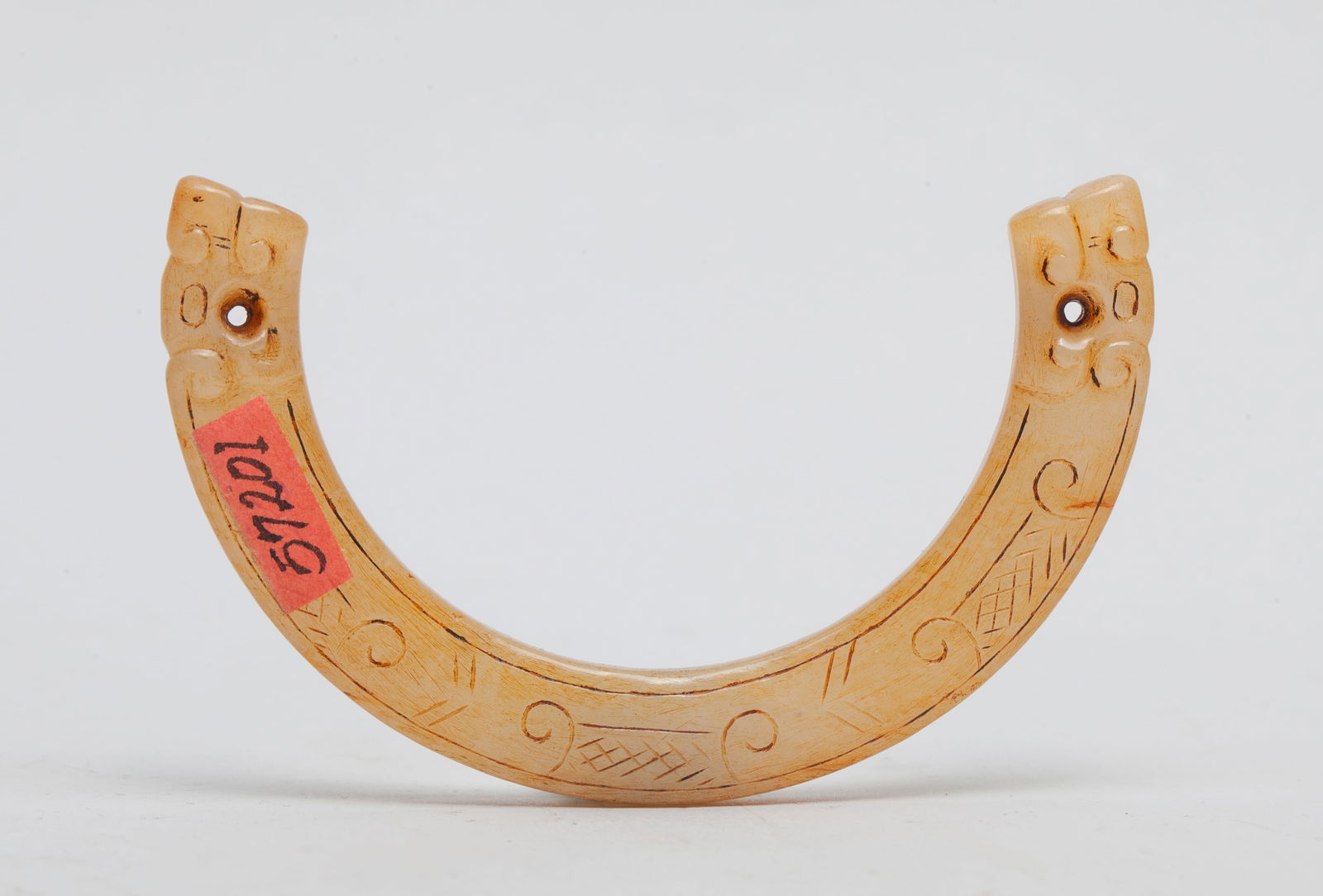 Chinese Chicken Bone Color Jade Huan: Of arch shape, carved on either terminal with a dragon head, the body incised with scrolls, pierced at the both terminals. Approx. 3.1*1.8 inch.