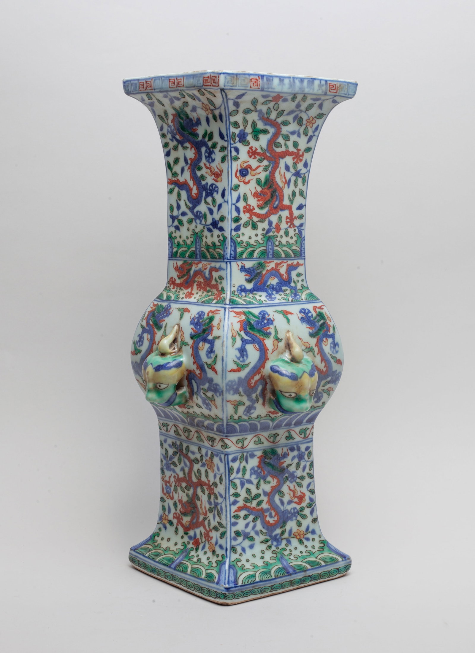 Tall Chinese Wuchai Porcelain Vase: Of square section, the central bulb rising from a splayed foot to a flared mouth, set with four raised beast masks at the bulb, painted on each side with dragon pursuing flaming pearl amongst leafy fo