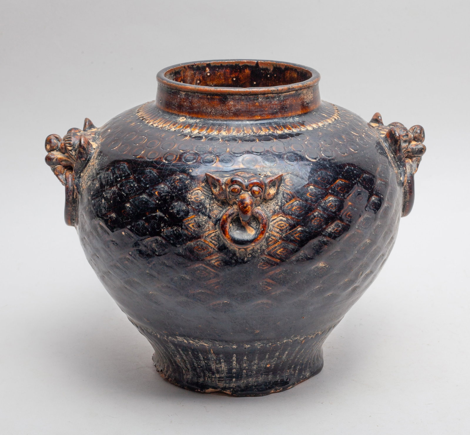 Chinese Sanchai Stoneware Large Bowl: Of tapered ovoid form, set with four raised beast masks hanging faux loops, carved around the body with traditional motif in low relief, the exterior and interior rim applied in crackled black glaze. 