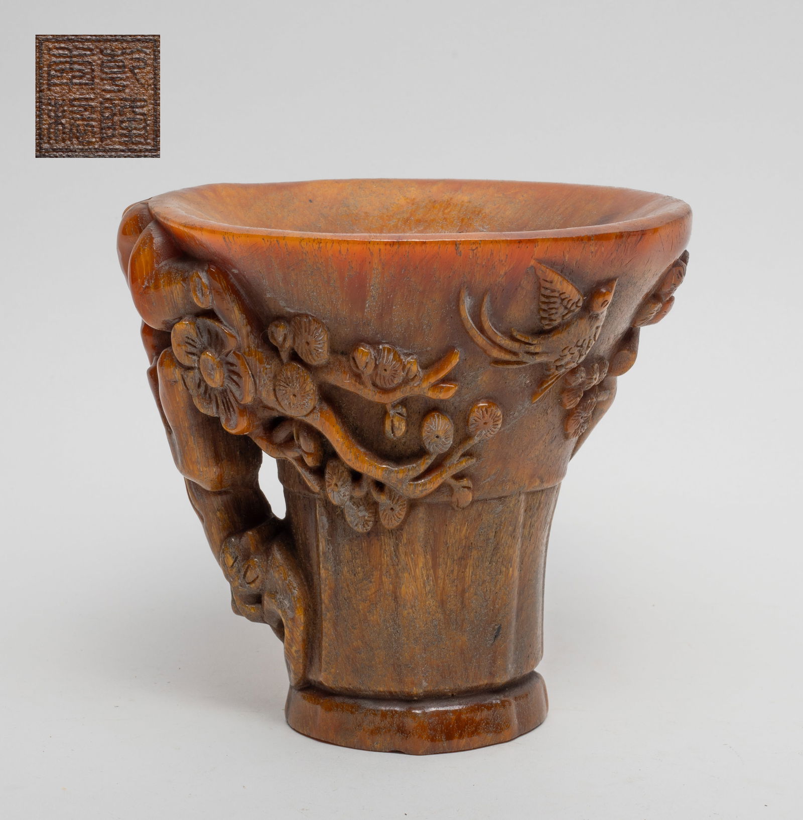 Chinese Carved Tall Cup: The tall cup carved in high relief with a gnarled tree as the handle, issuing plum blossoms and pine needles, with two birds, the bottom incised with a seal mark. Approx. 5.75*5.5*4.6 inch.