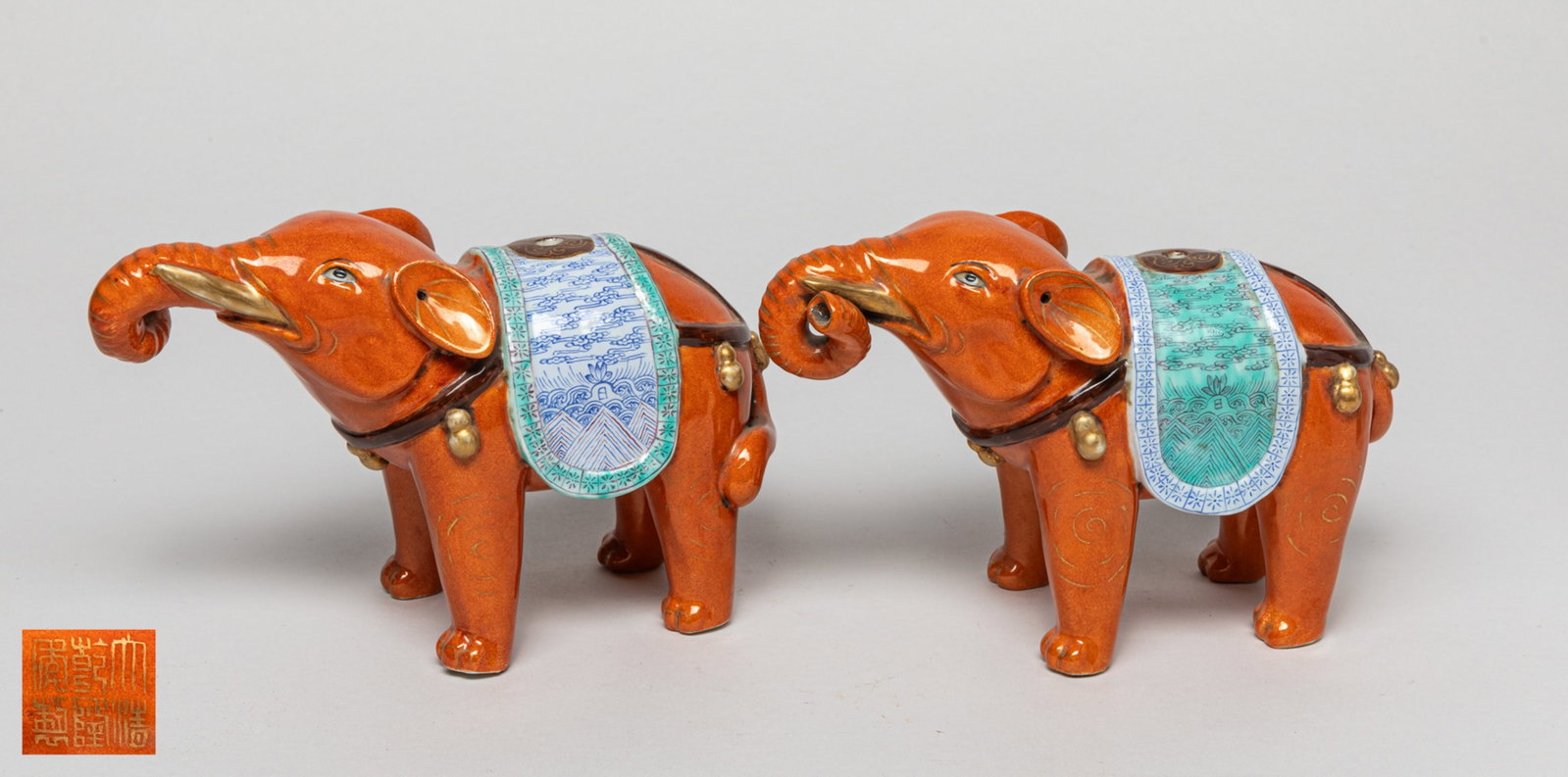 Pair Chinese Porcelain Elephant Sculptures: A pair of Chinese porcelain elephant sculptures glazed in orange color, a blanket-shape on its back with small hole in the center, two ears pierced with a hole. Approx. 7.2-3.2-4.7 inch (each).