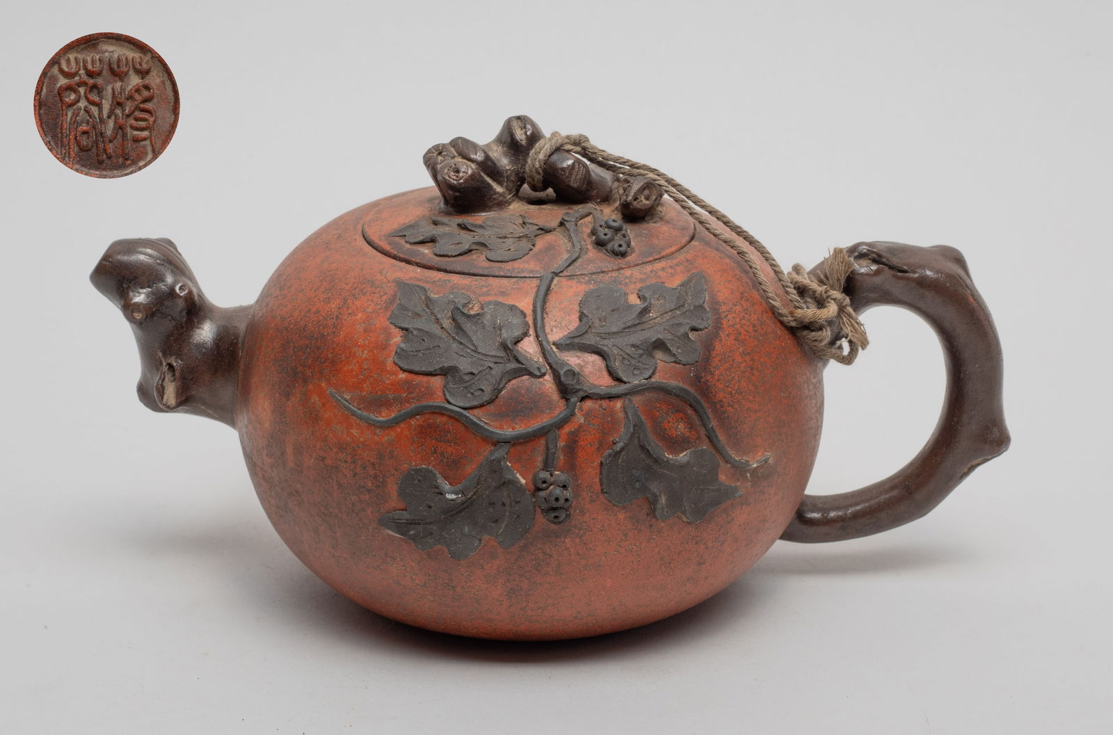 Chinese Yixing Zisha Tea Pot: Of globular form, carved in raised relief with grape vines around the body and lid, the handle and spout worked in stem form, the bottom with a circular mark. Approx. 7.1*4.8*3.9 inch.