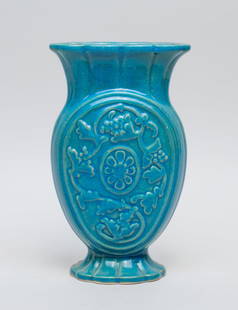 The Cowan Pottery Studio Vase: Of flattened ovoid form rising from a splayed foot to a flared neck, carved on both sides with grape vines and flower, covered overall save for the base in turquoise blue glaze, the bottom carved Cowa