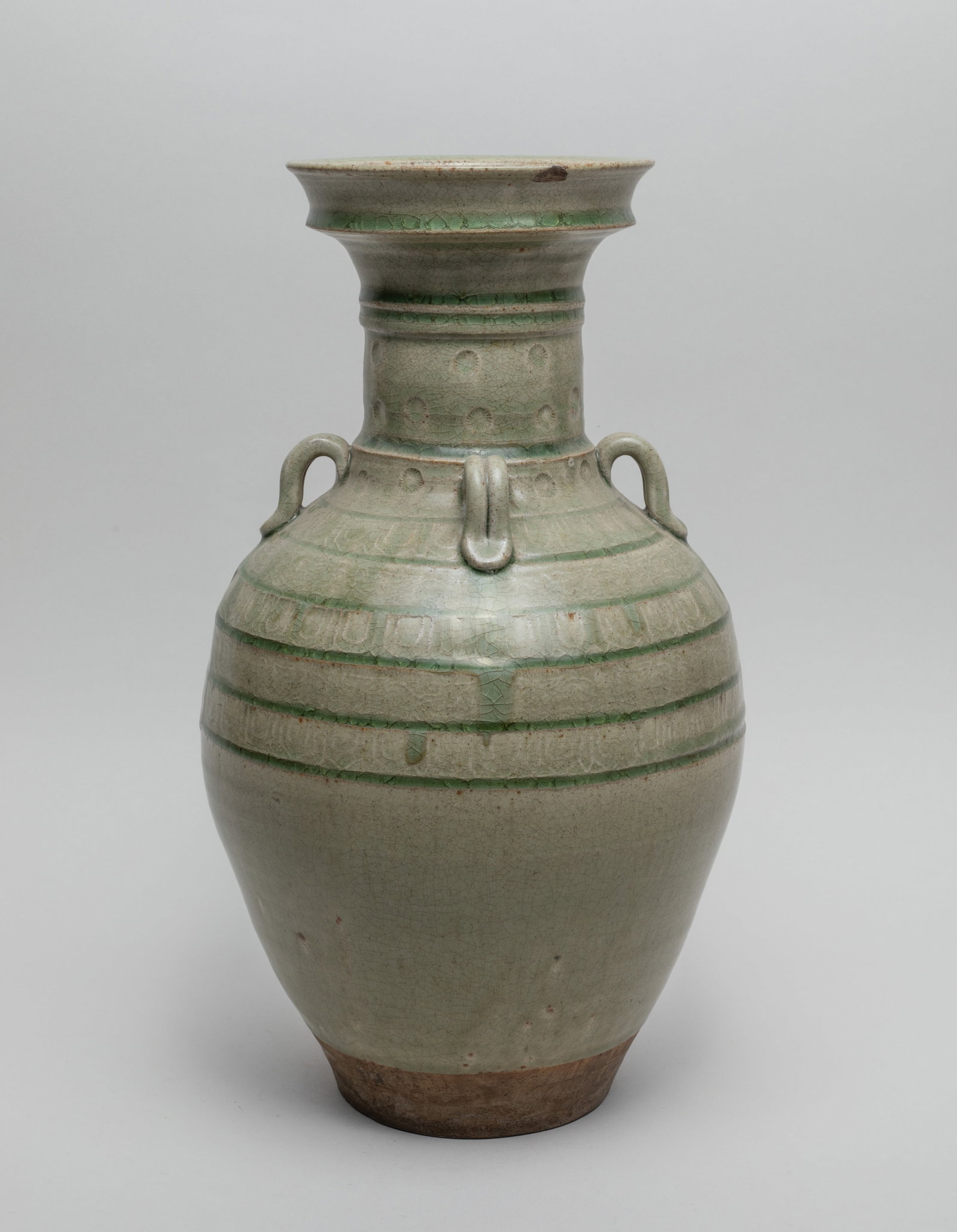Tall Chinese Yue Ware Porcelain Vase: The ovoid body rising to a cylindrical neck and a dished rim, set with four handles at the neck, carved with borders, lotus petals and flowers around the neck and upper body, overall covered in crackl