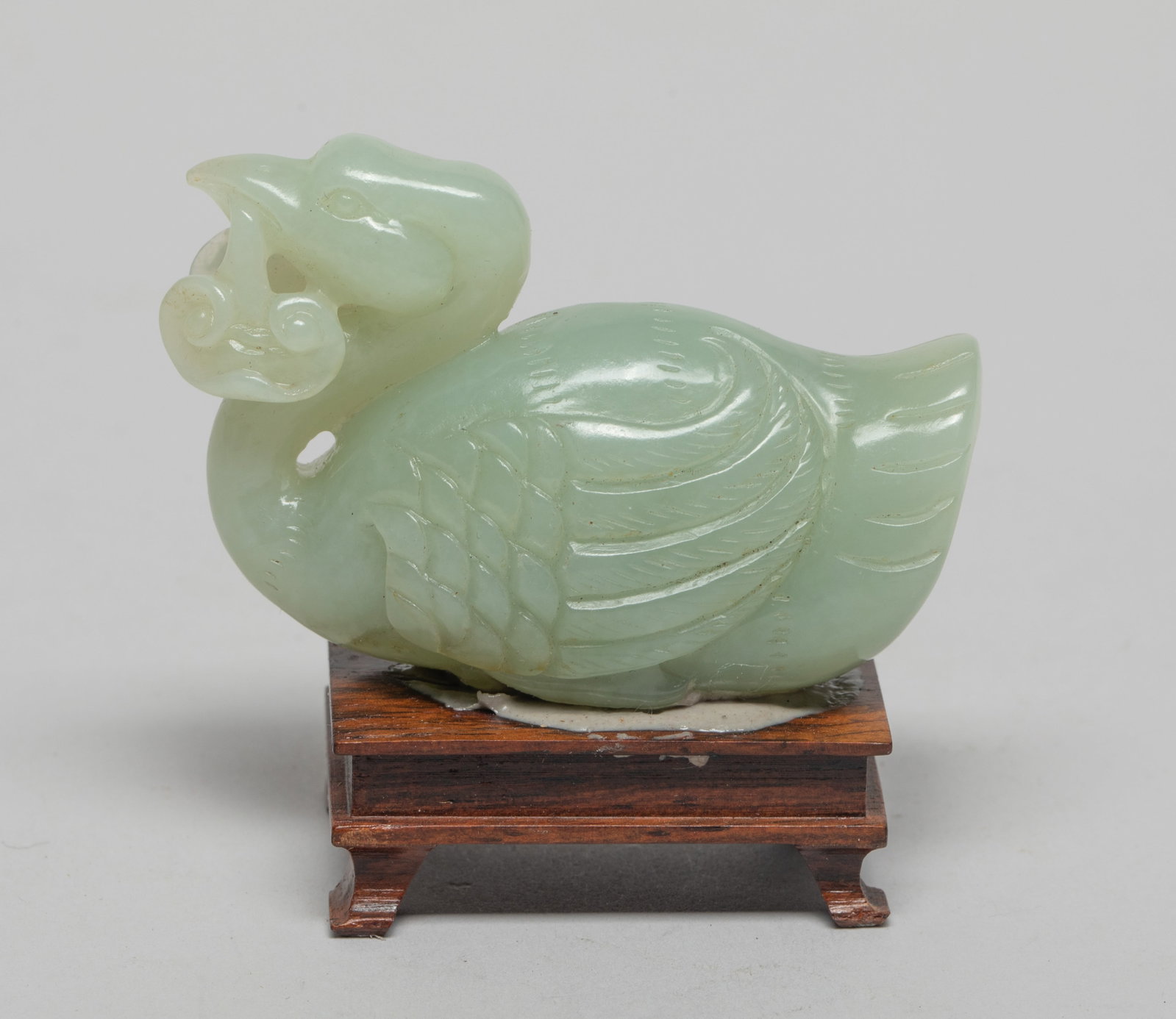 Chinese Jade Carving of Goose: Carved as a recumbent goose clutching lingzhi in the mouth, the legs tucked beneath its body, with stand. Approx. 2.38*1.6*1 inch (w/o stand).