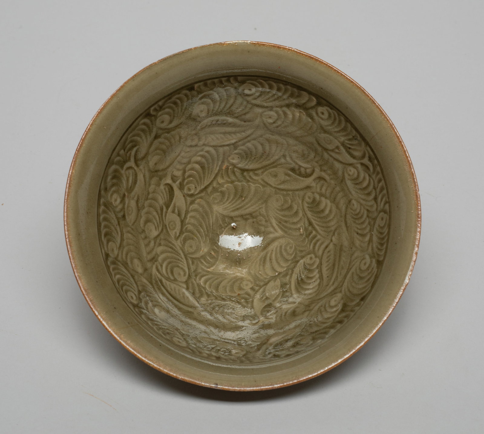 Chinese Yaozhou Ware Porcelain Tea Bowl: The bowl interior walls carved with fish among scrolling leaves, overall covered in dark olive green glaze except the foot. Approx. 4.8*2 inch.