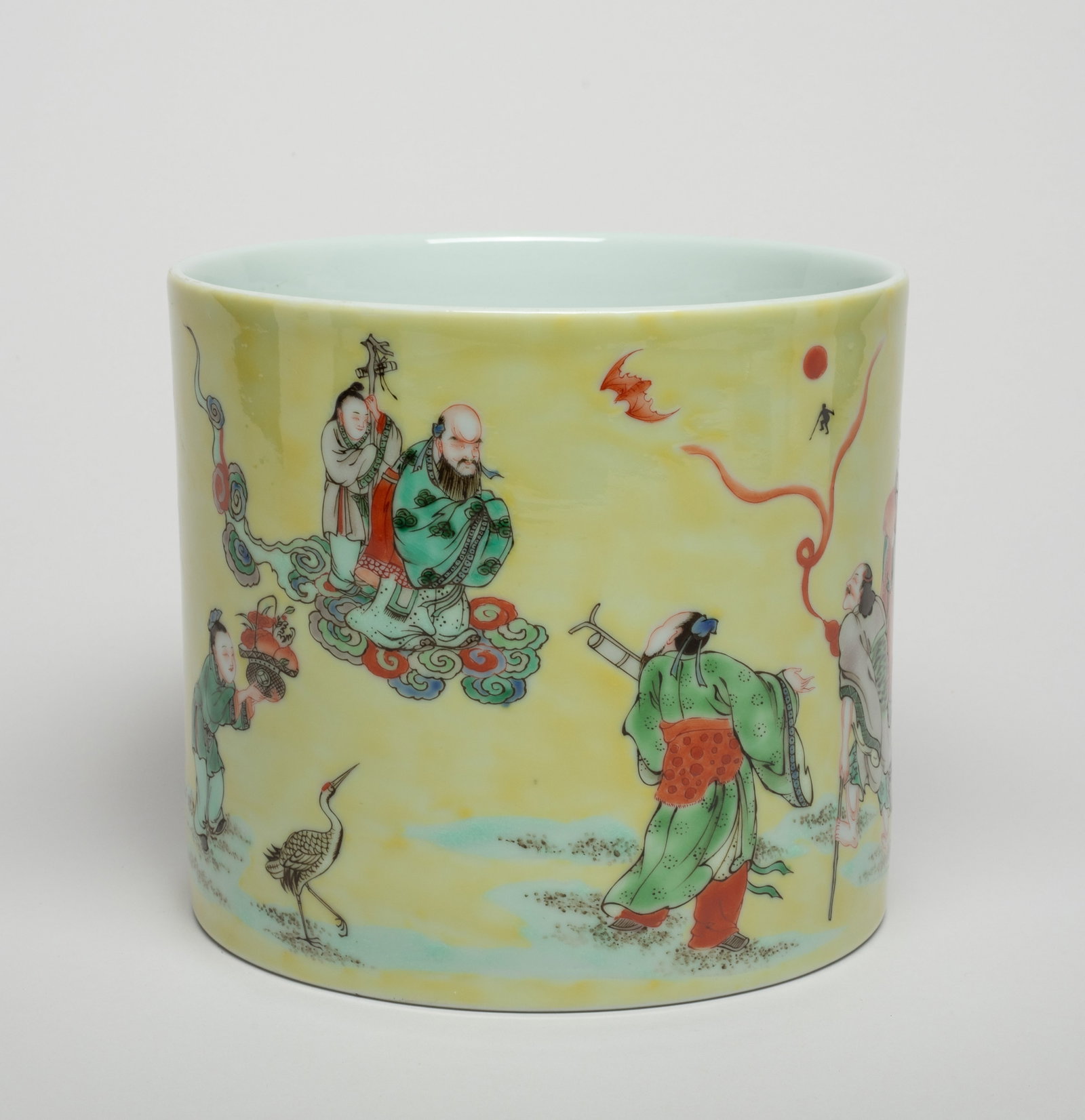 Chinese Famille Rose Porcelain Brush Pot: Of cylindrical form, the exterior decorated with immortals in various activities on pale yellow ground, with bats, pine tree and lingzhi. Approx. 7.4*6.5 inch.