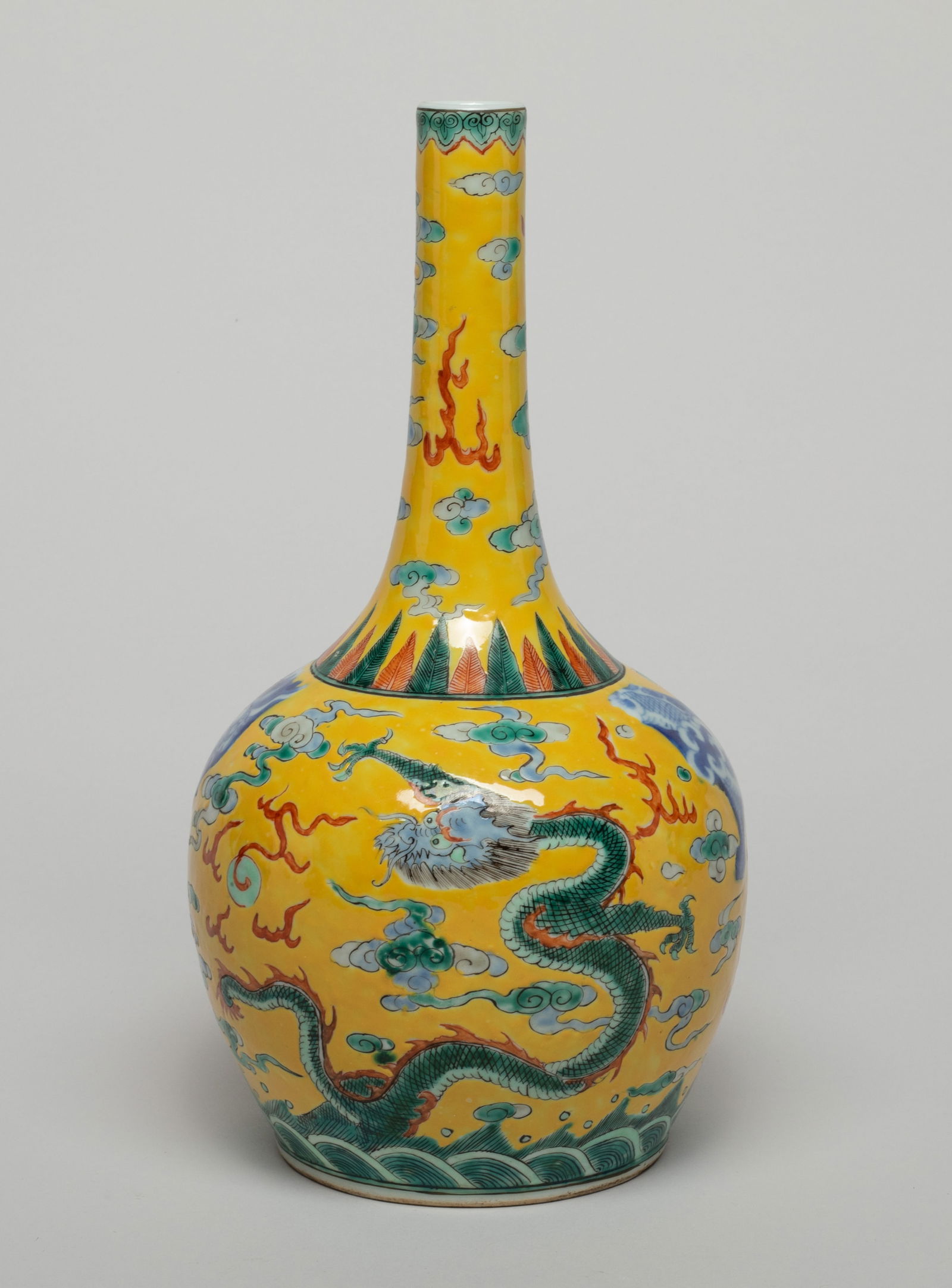 Chinese Export Porcelain Cabinet Vase: The ovoid body rising to a tall slender neck, enameled with dragons pursuing flaming pearls amidst flames and clouds, above waves and against yellow ground. Approx. 10.1*5.2 inch. The Estate of the F.