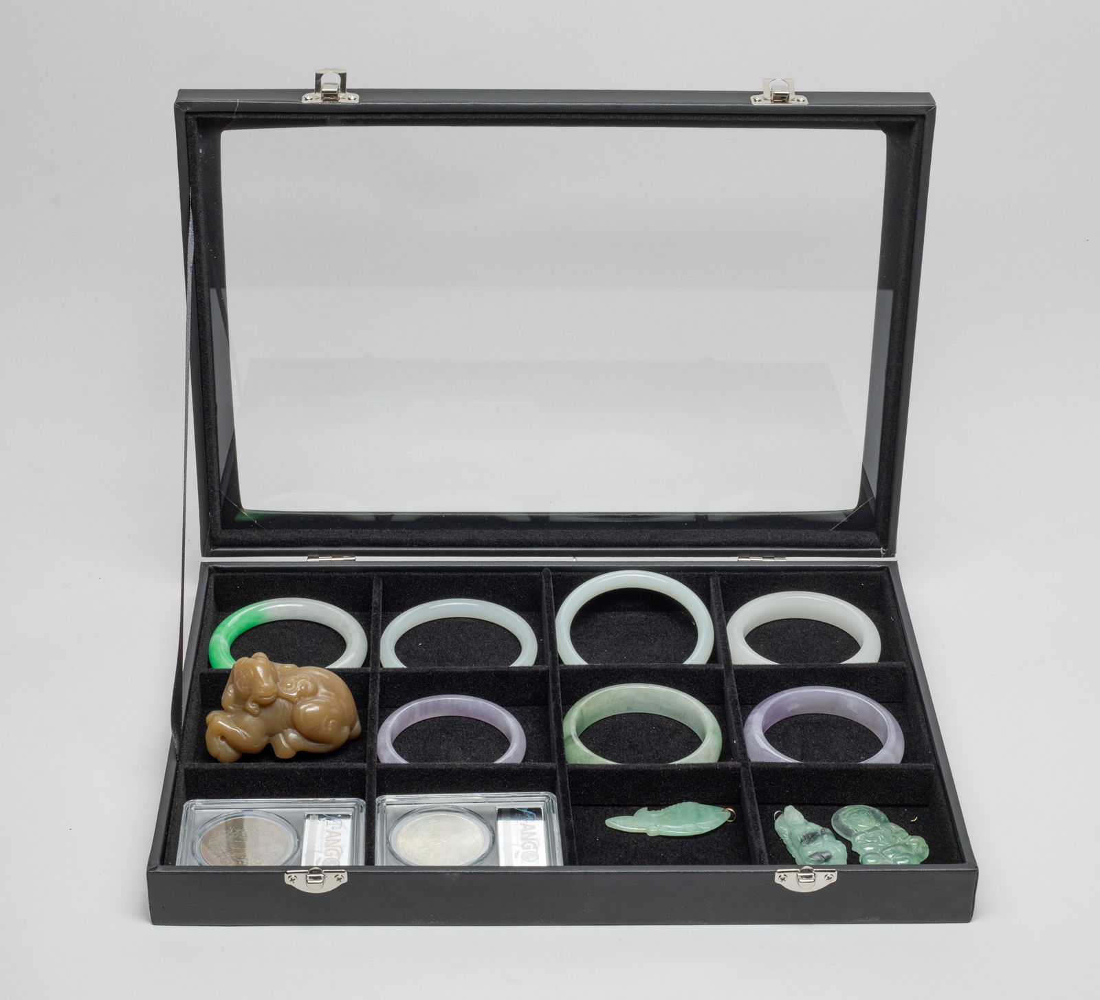 Chinese Bangles, Fengshui Coins & Stones: Including 7 Chinese colored stone bangles, 2 Fengshui coins, a sculpture carved as a recumbent goat holding lingzhi in mouth, and 3 pendants carved in Buddha or fish form, with case. Approx. 2.87*2*1.