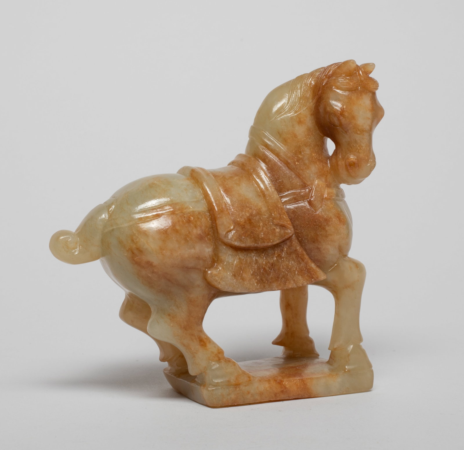 Chinese Russet Jade Sculpture of Horse: The horse carved standing foursquare on a rectangular base, the head turned slightly to the right, with a curled tail. Approx. 4.6*4.4*1.5 inch.