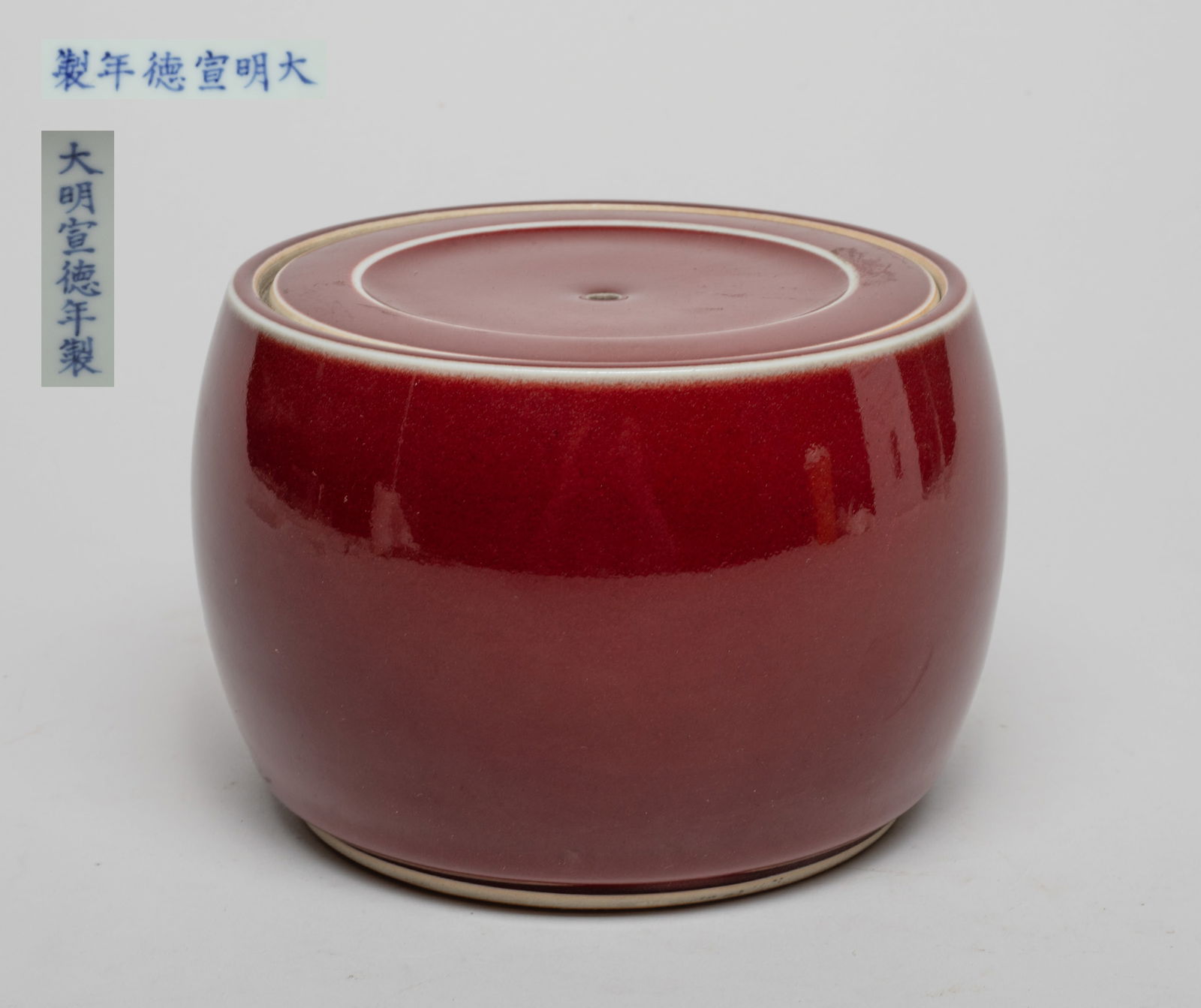 Chinese Red Glazed Porcelain Covered Jar: Of drum form, the exterior covered in even dark-red glaze, the lid interior and the jar bottom marked with six characters in underblue glaze on white ground. Approx. 5.85*3.9 inch.