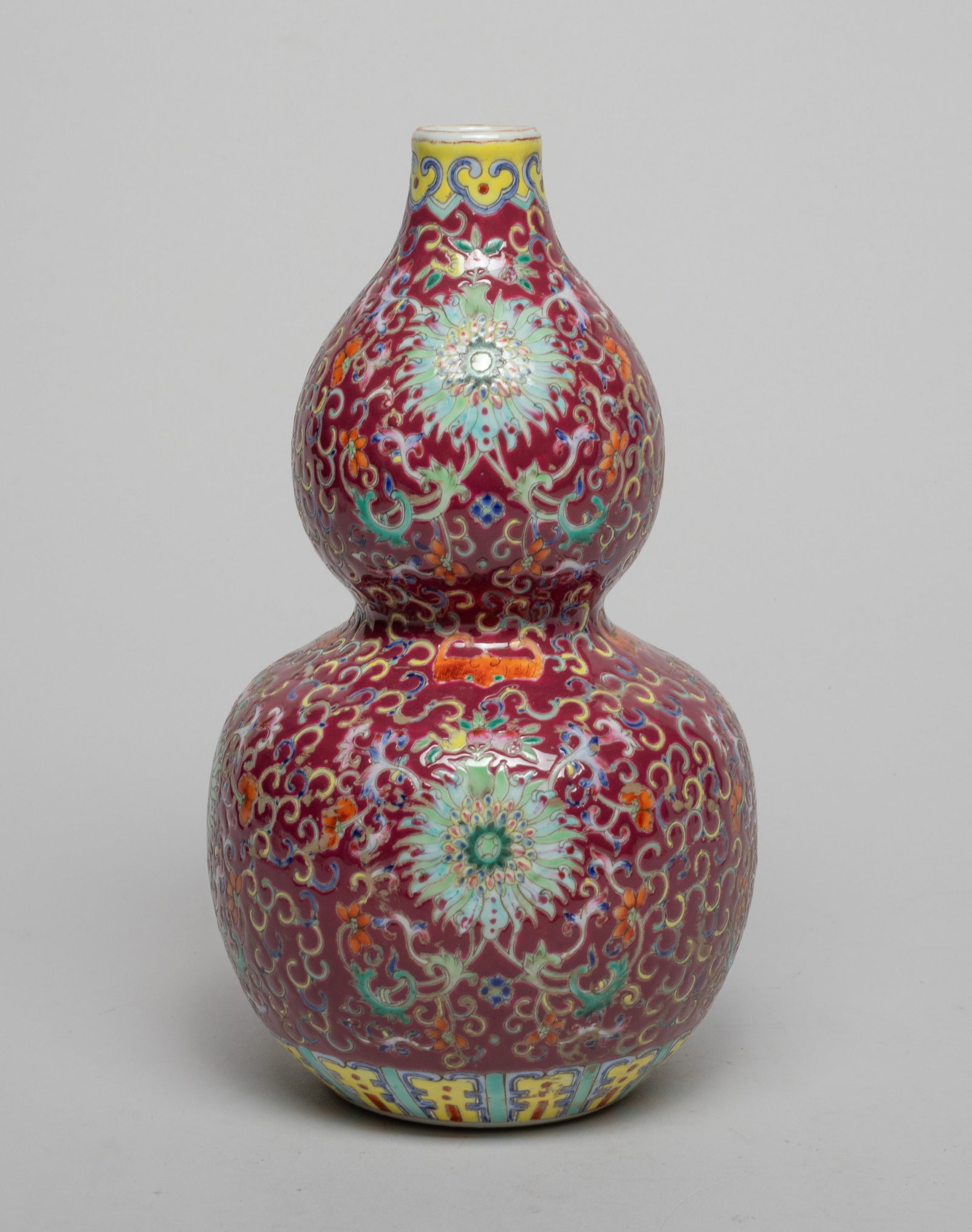 Chinese Famille Rose Porcelain Gourd Vase: Of double gourd form, the exterior enameled with dense lotus foliage on dark rosy pink ground, interspersed with bats and shou characters, between bands of ruyi heads and lappets. Approx. 9.3*5.1 inch
