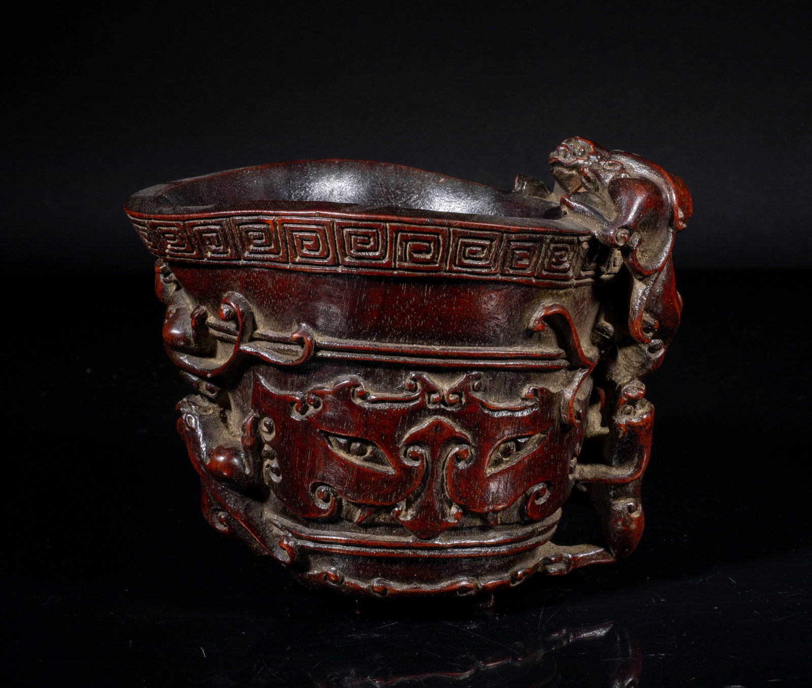 Chinese Bark of Agarwood Cup: The cup exterior decorated in low relief with taotie masks, the rim with a band of key-fret, one side of the vessel with three clambering chilong, the reverse modelled as two sinuous chilong, the bott