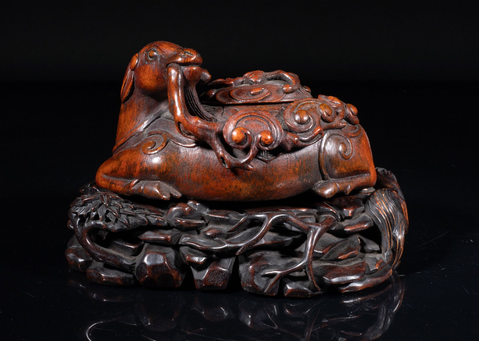 Chinese Bamboo Water Pot w/ Zitan Stand: Chinese bamboo water pot carved in recumbent sheep form, the head turned backwards grasping a lingzhi stem in the mouth, with a bat on its back, the Zitan wood stand carved with bamboo, pine tree, lin