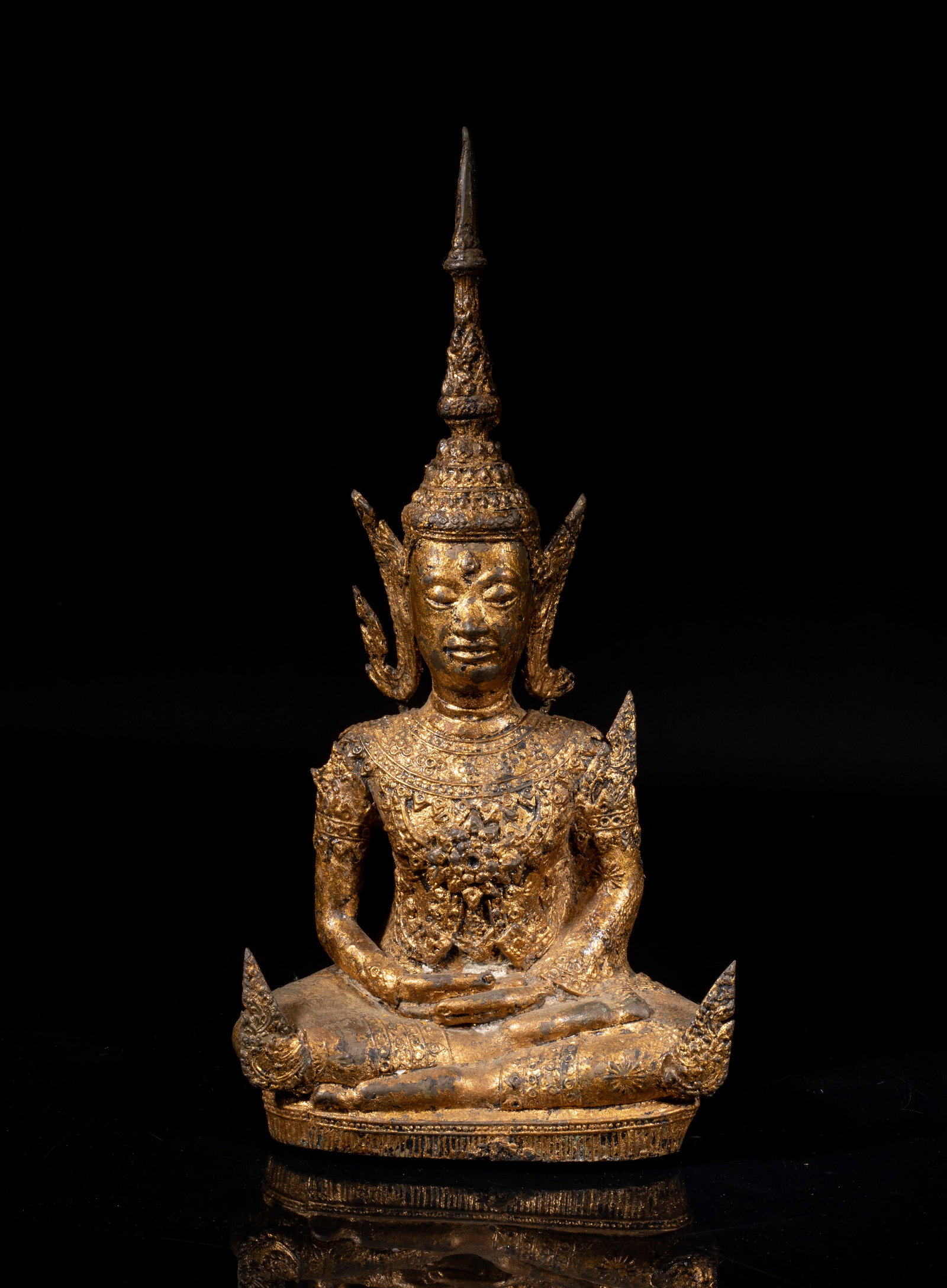 South Asian Gilt Bronze Buddha: The seated Buddha wearing jeweled raiment and a tall elaborate diadema, his hands in bhairava mudra, the meditative face with serene expression, the half open eyes looking downwards. Approx. 12.7*6*3.