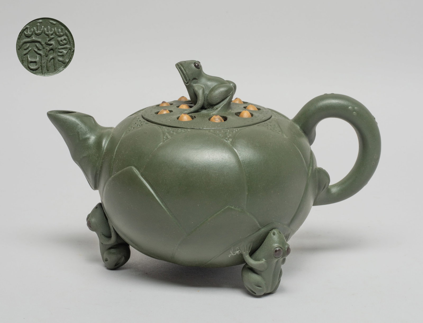 Vintage Chinese Yixing Zisha Tea Pot: Moulded in lotus form resting on three frog form feet, the seedpod form lid set with a frog knob, the lid interior carved with a mark and the bottom carved a circular mark. Approx. 6.6*4..3*4.1 inch.