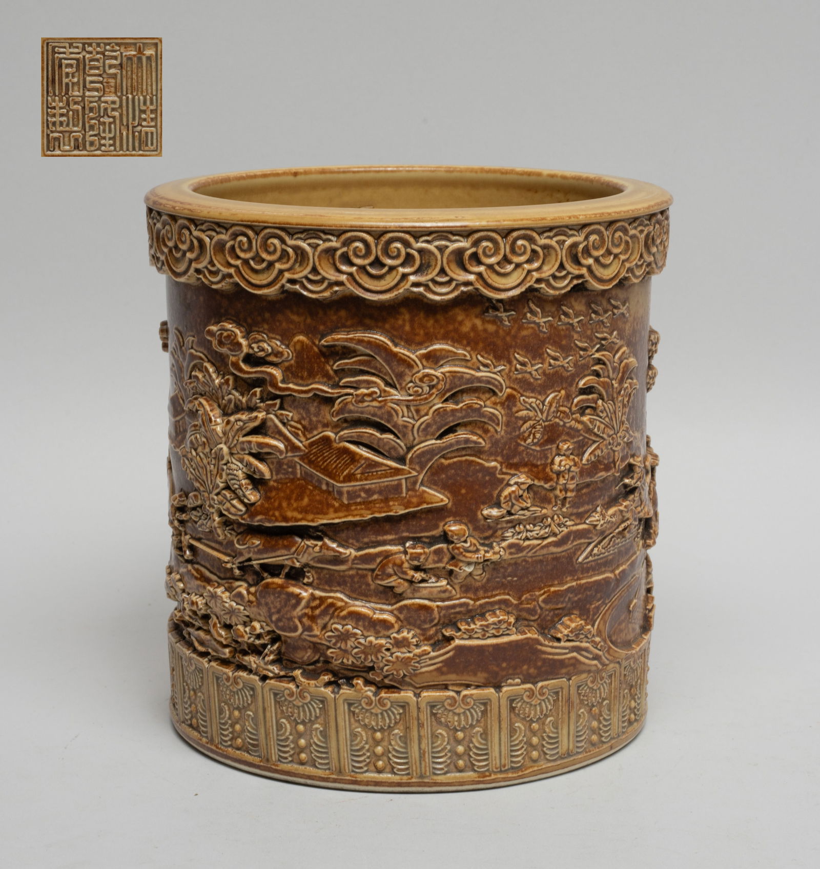 Chinese Salt Glazed Porcelain Brush Pot: The cylindrical body exterior carved in raised relief with a continuous scene of figures in various activities in landscape setting, the bottom incised with a seal mark. Approx. 5.6*5.5 inch.