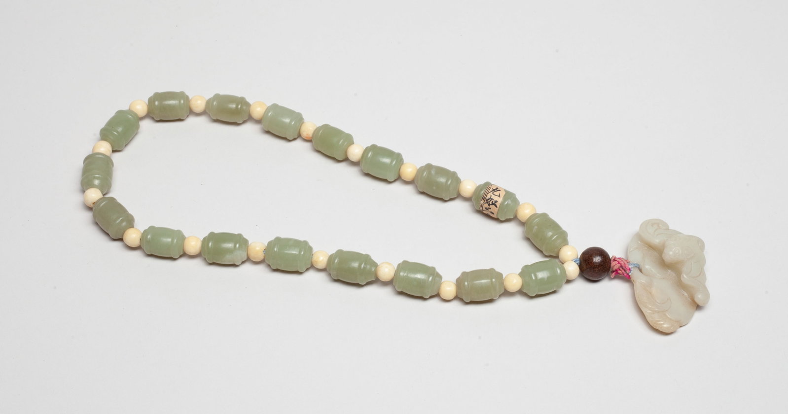 Chinese Jade Prayer Beads: A string of Chinese pale celadon jade carved prayer beads, spaced by bone beads, suspended with a wood bead and a white jade pendant carved with bat and peaches. Approx. 1.9*1.2*0.7 inch (jade pendant
