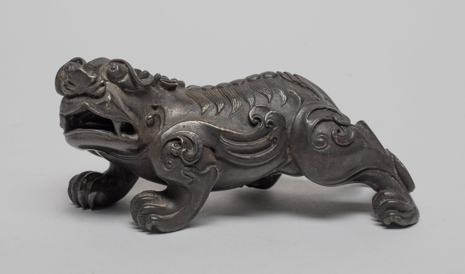 Collectible Chinese Metal Table Sculpture: Chinese metal horned beast cast in crouching pose, detailed with protruding eyes, wide nostrils and open mouth baring its fang. Approx. 4.6*2.2*2.1 inch.