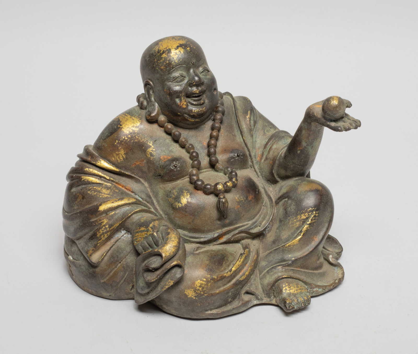 Chinese Export Bronze Buddha: The laughing Buddha wearing a loose-fitting robe open at the chest, the left hand holding a ball and right hand grabbing a bundle. Approx. 6*5.5*4.5 inch.