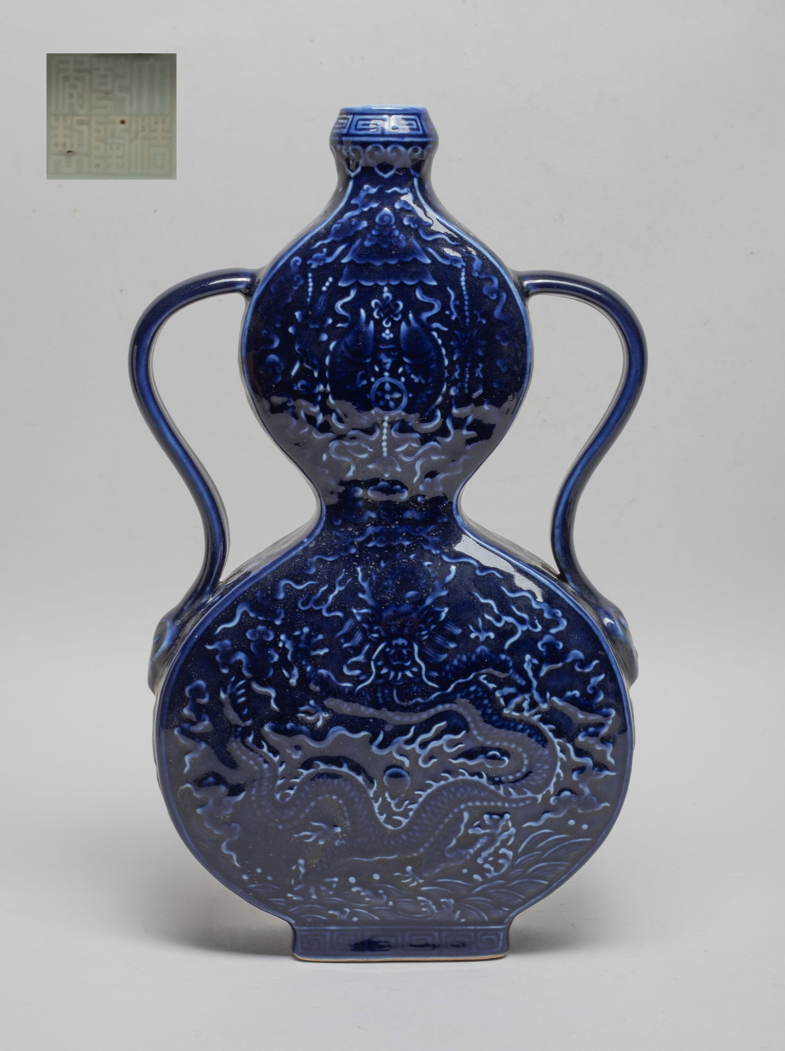 Chinese Blue Glazed Porcelain Gourd Vase: Of flattened double gourd form with two handles, the upper bulb carved with pair of fish, traditional instrument and lotus, the lower bulb carved with dragon pursuing pearl amidst clouds, the exterior