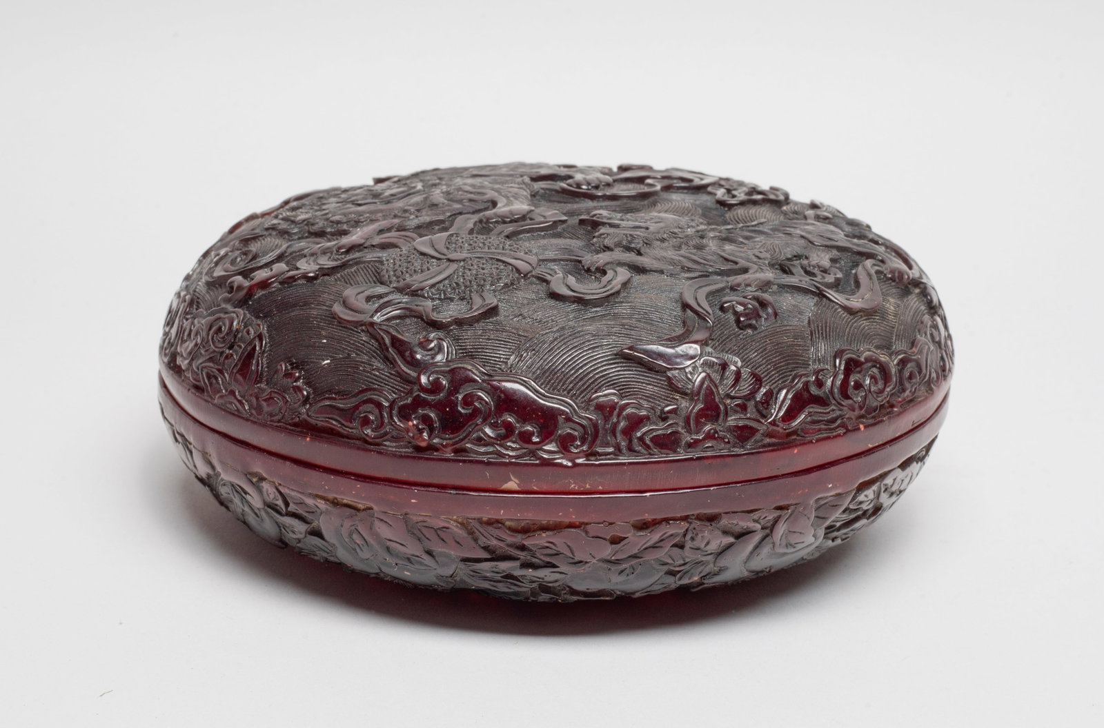 Chinese Export Beads Collective Box: The convex surface of the cover carved with a lion and cub chasing ribbons from an circular ball set against a wave background that continues across exterior wall of the similarly shaped box displayin