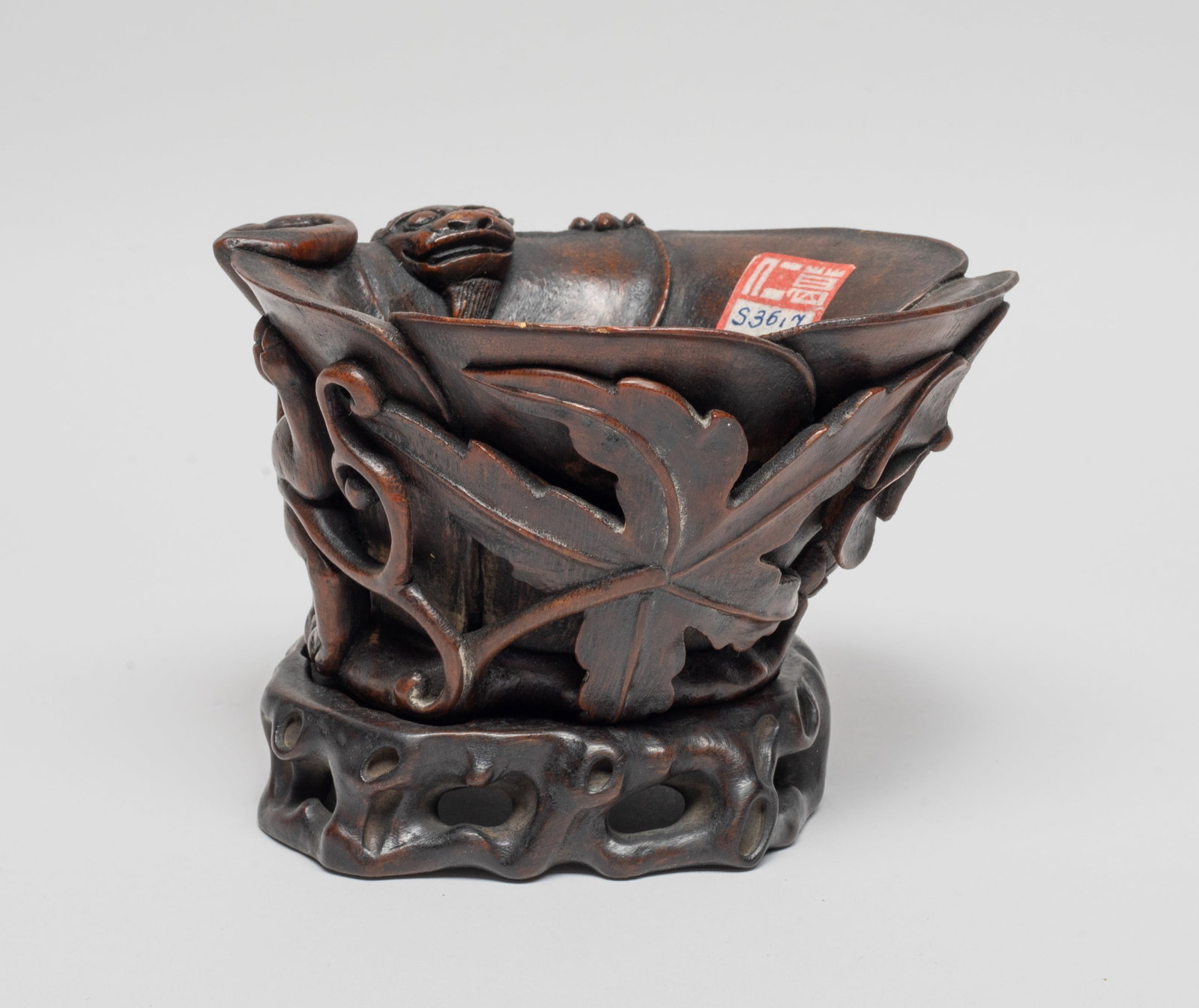 Estate Chinese Bark of Agarwood Cup: The tapering walls formed of overlapping petals rising to the slightly flared undulating rim, finely carved in relief with a blossom and buds borne on naturalistically carved stems emanating from a ne