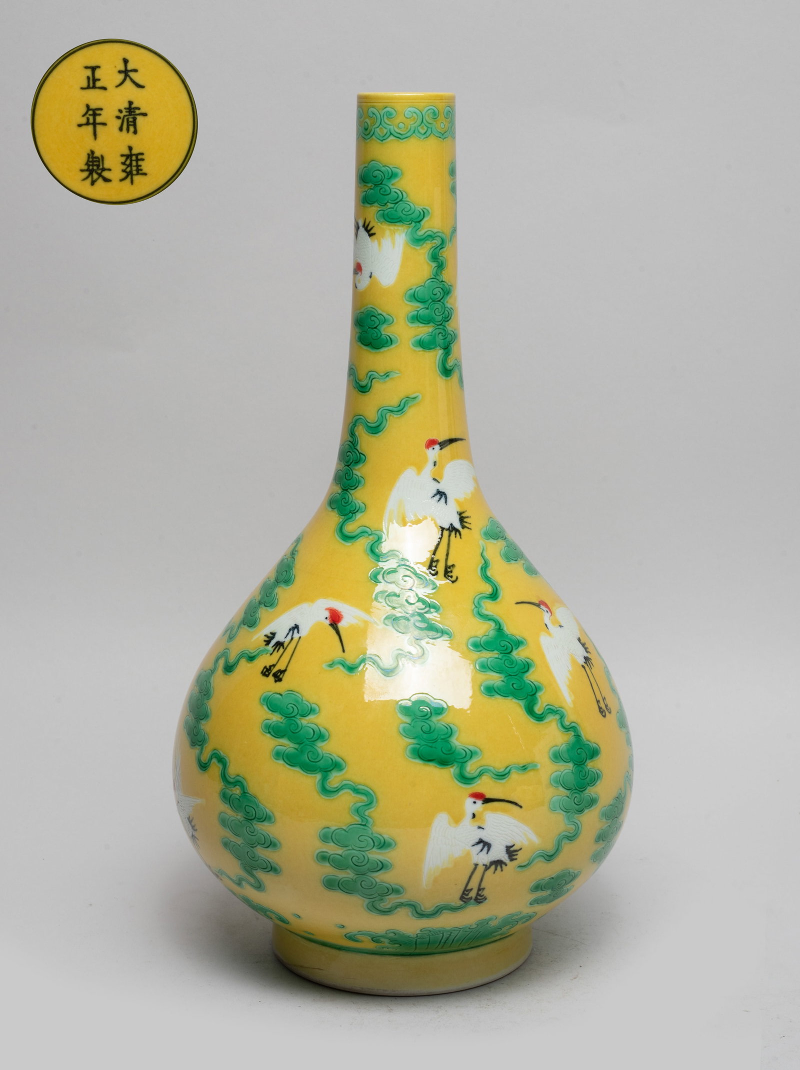 Chinese Export Porcelain Vase: The pear-shaped body rising from a short foot to a tall slender neck, the exterior painted with cranes among scrolling clouds on yellow-glazed ground, the bottom marked with six characters enclosed in