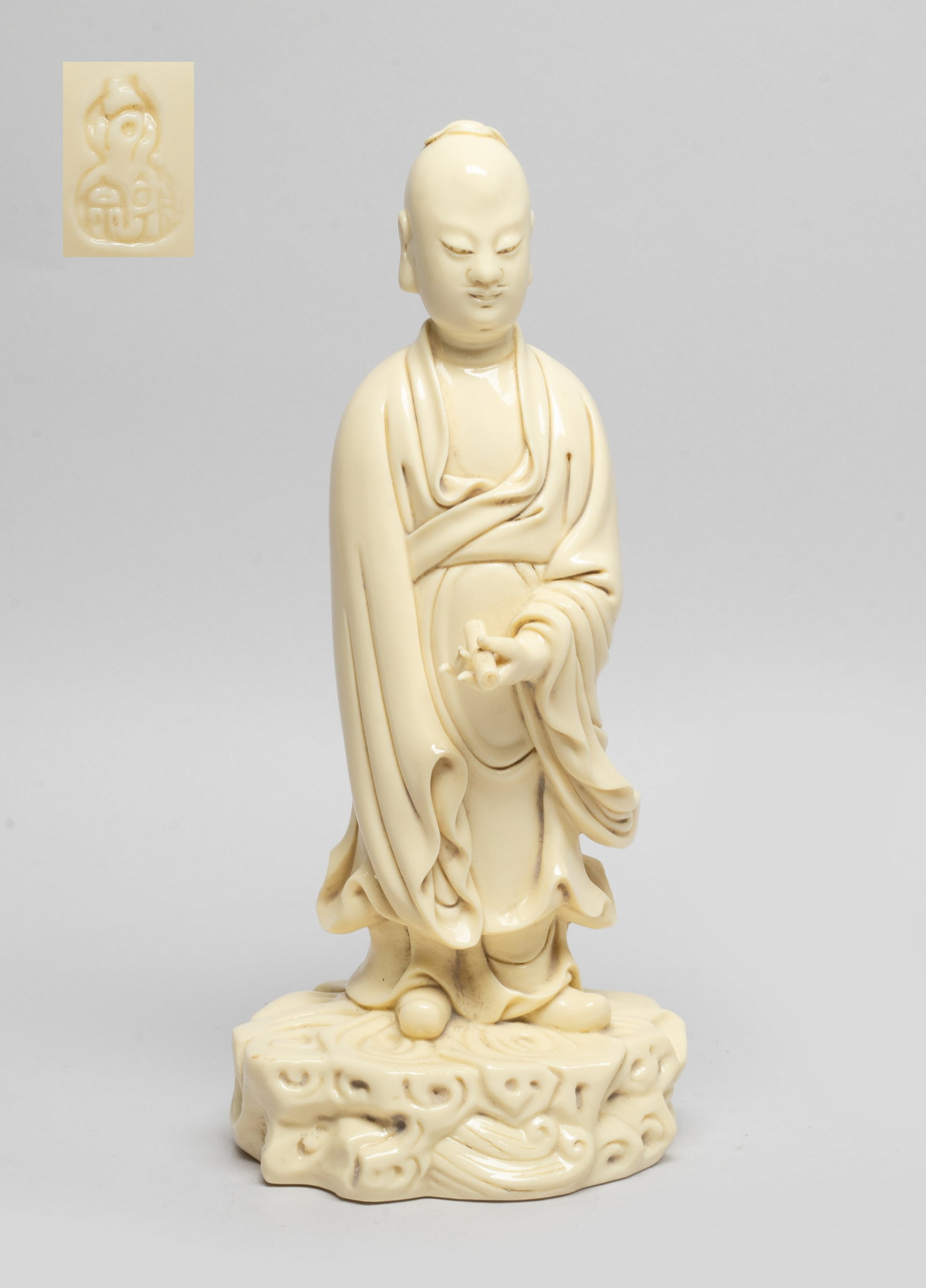 Chinese Blanc De Porcelain Figure: Moulded as a standing scholar wearing a long flowing robe, the left hand holding a scroll book, the exterior applied in even beige glaze, the back incised a double-gourd shaped mark. Approx. 9.8*4.4*3