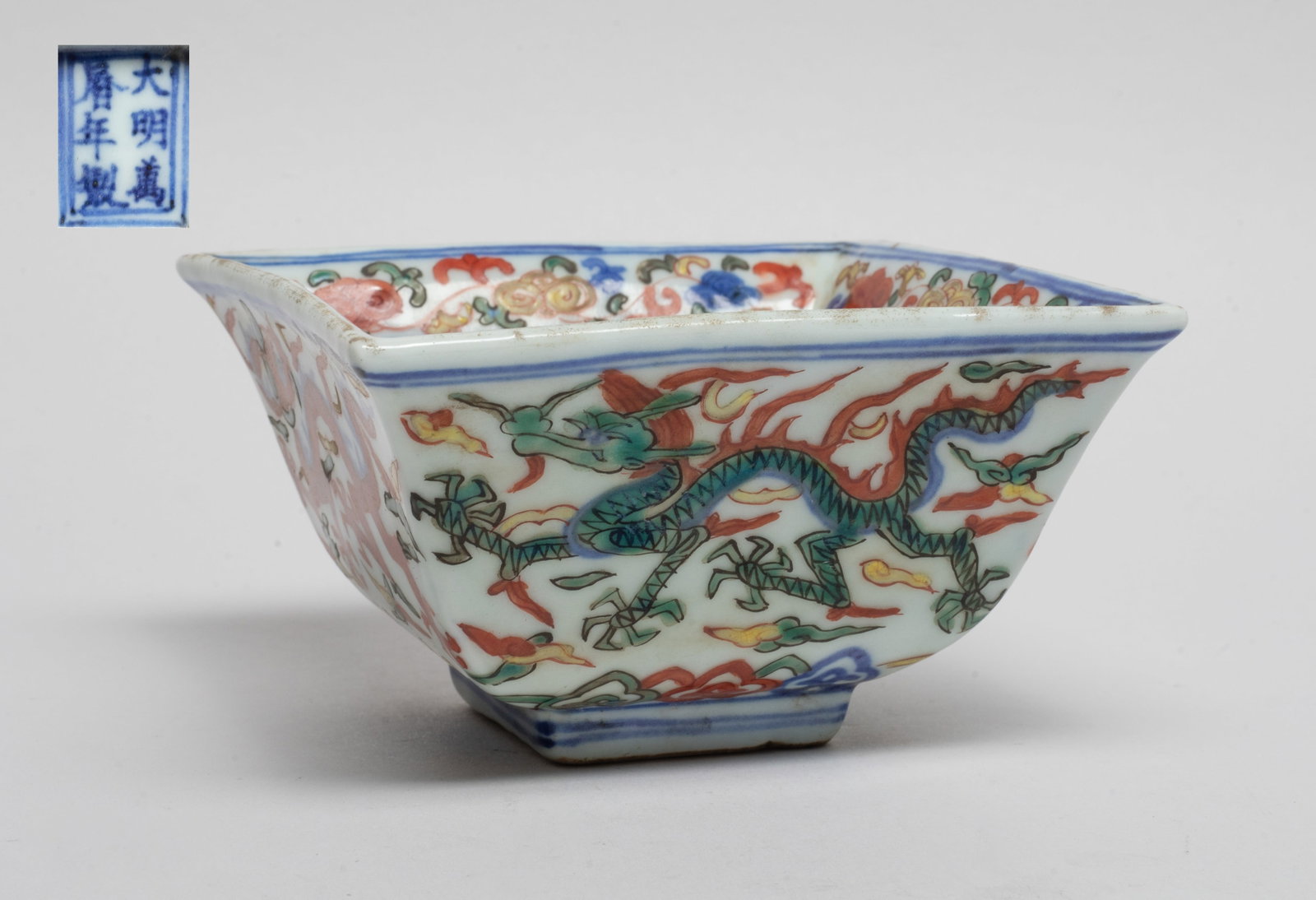 Chinese Wuchai Porcelain Bowl: Of square section, the exterior sides and the interior centre painted with five-clawed dragons amidst clouds, the interior rim painted lingzhi sprays, the bottom with a seal mark. Approx. 4.3*4.3*2.4 