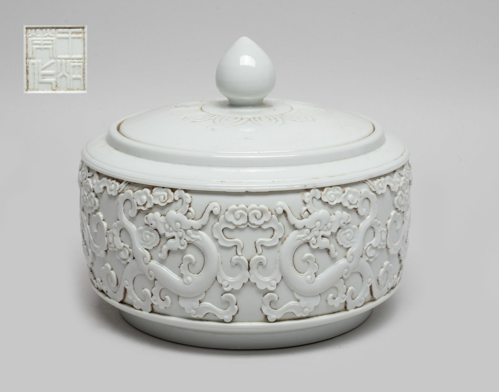 Chinese Molded Porcelain Covered Pot: The pot body carved in raised relief with dragons amidst clouds, overall covered in even white glaze, the bottom incised with a four-character mark. Approx. 5.2*6.3 inch.