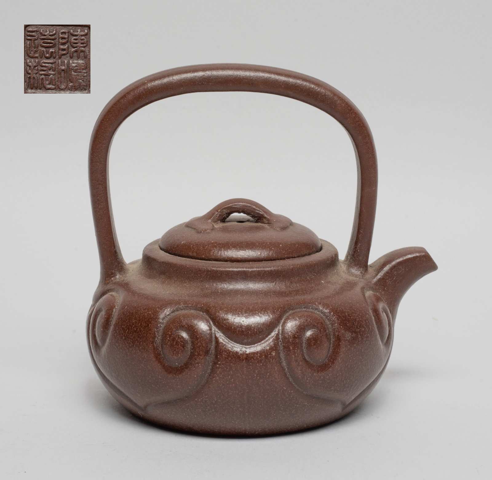 Chinese Yixing Zisha Tea Pot: The teapot body carved with ruyi heads, the bottom incised with a four-character mark. Approx. 5*5.2*4.6 inch.