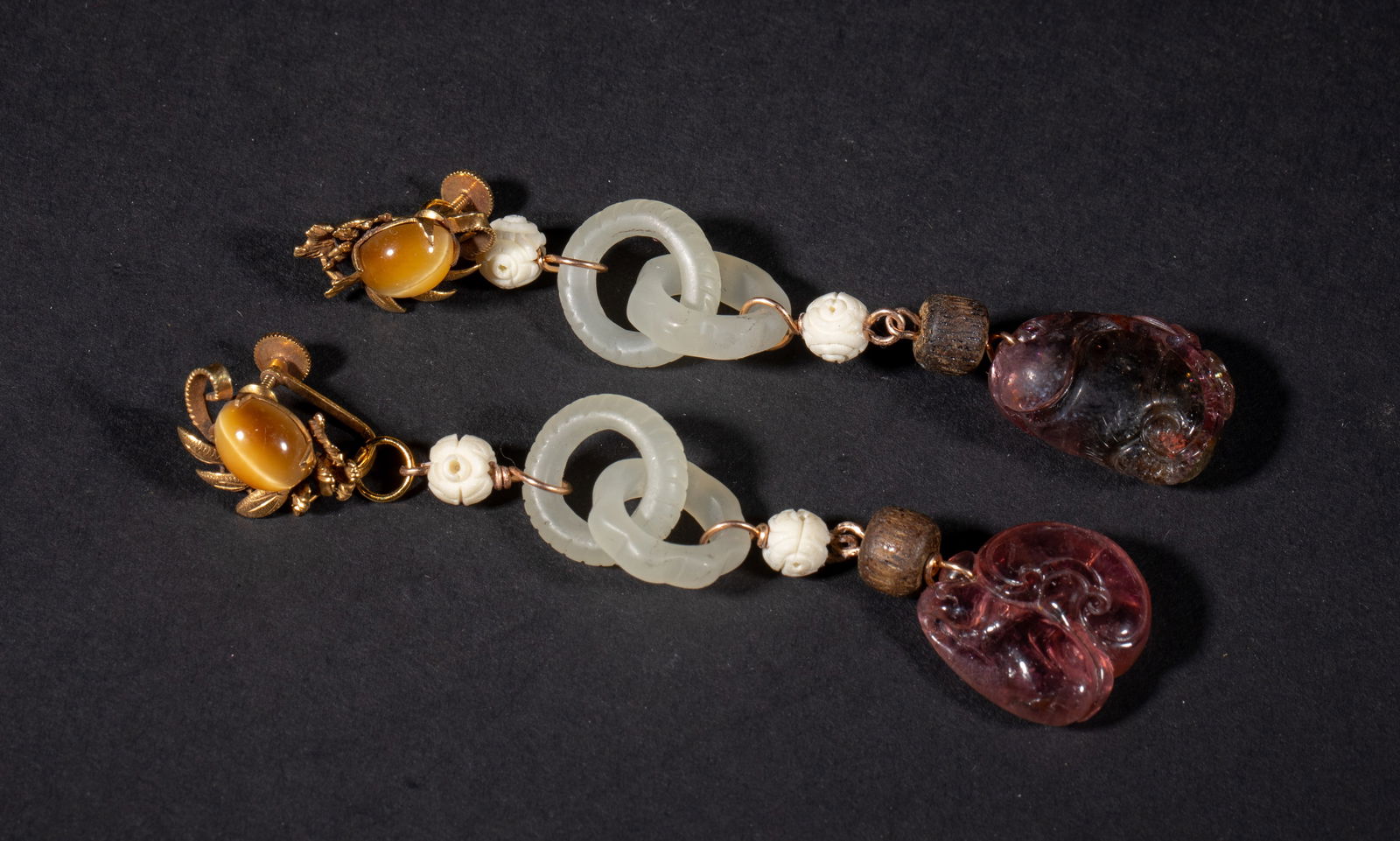 Marked 14k Gold Chinese Tourmaline Earrings: A pair of delicate Chinese earrings marked 14K, comprised of gemstone pebbles, bone beads, wood bead, jade / stone carved interlocking loops, and tourmaline toggles carved with lingzhi. Approx. 0.75*0