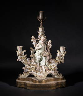 Large Italian Type Porcelain Table Lamp: Moulded as an elegant woman seated on a stand of flowers, holding a bowl of flowers in hands, two boys flying on her sides, with a bulb holder and two candlestick holders. Approx. 20.5*13*9 inch.