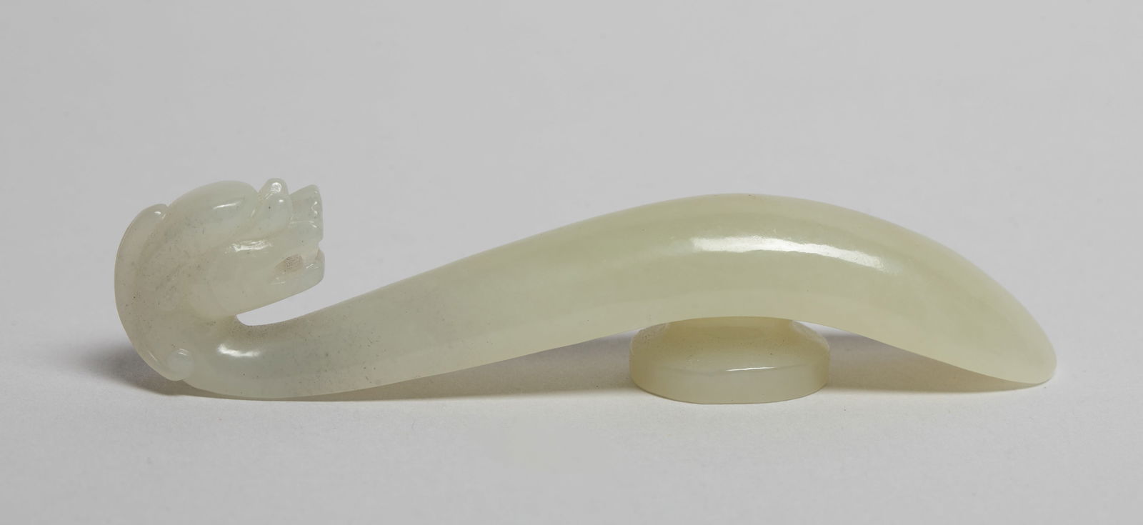 Chinese Jade Carved Belt Buckle: Of long concave section terminating at one end in a dragon head hook, the underside with a circular knob. Approx. 3.5*0.7*0.6 inch.