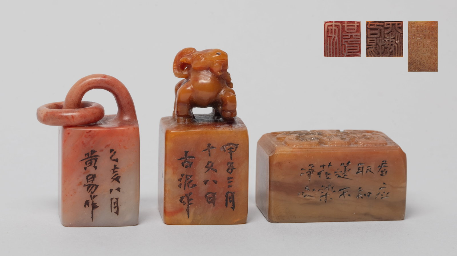 Estate Chinese Shoushan Stone Seals: Three reddish Shoushan stone seals, one carved with a taotie mask on the top, one carved with a goat holding lingzhi in mouth, the other with a raised loop handle. Approx. 1.9*0.9*0.9 inch (largest).