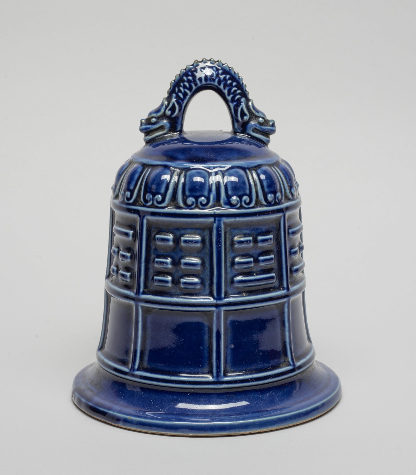 Chinese Blue Glazed Porcelain Sculpture of Bell: The bell exterior carved with Daoist Eight Trigram symbols, set with a dragon handle on the top, the exterior applied in dark blue glaze. Approx. 6.5*8 inch.
